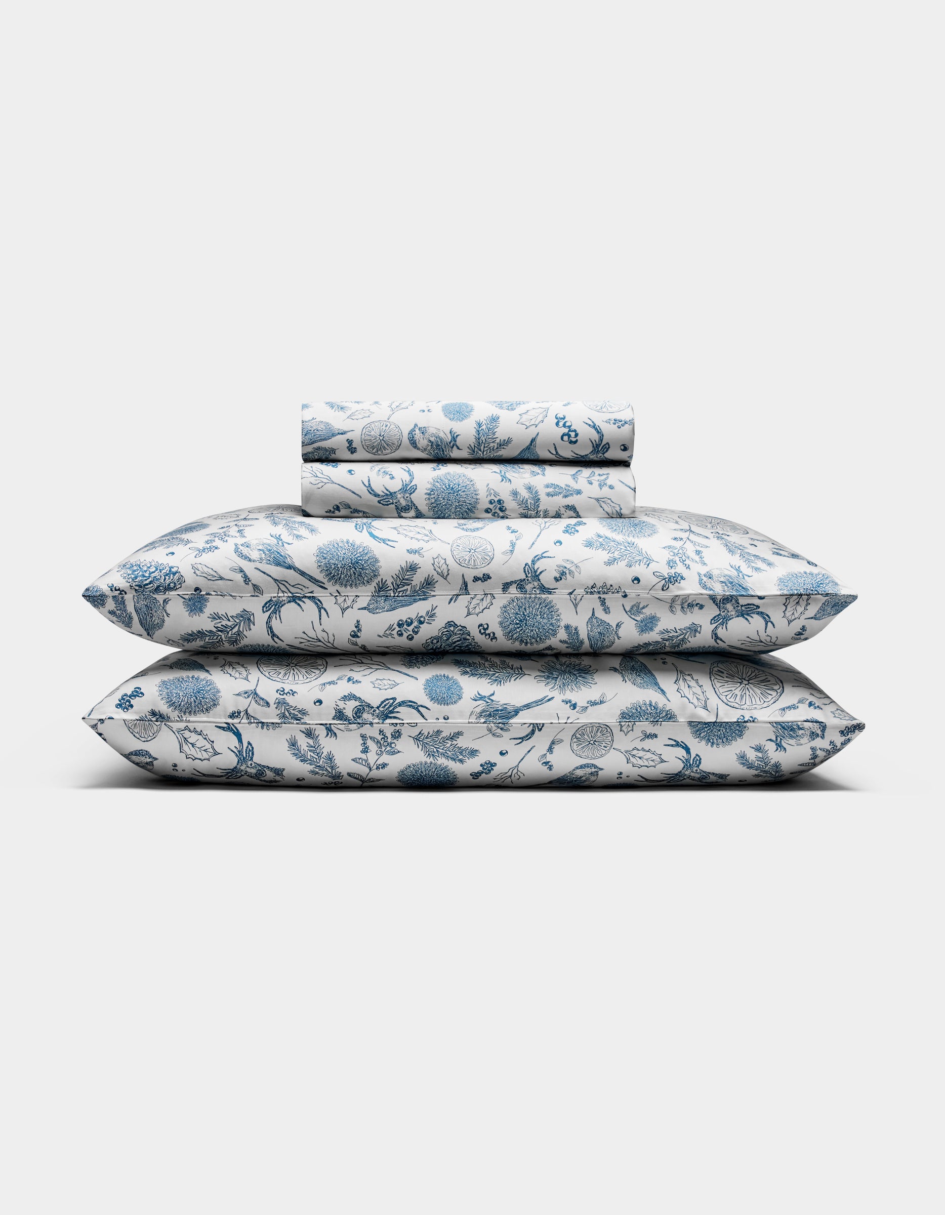 The Cozy Earth Bamboo Sheet Set, featuring pillowcases and sheets with a blue floral pattern on a white background, is neatly folded and displayed against a plain white backdrop.|Color:Winter Toile Pacific