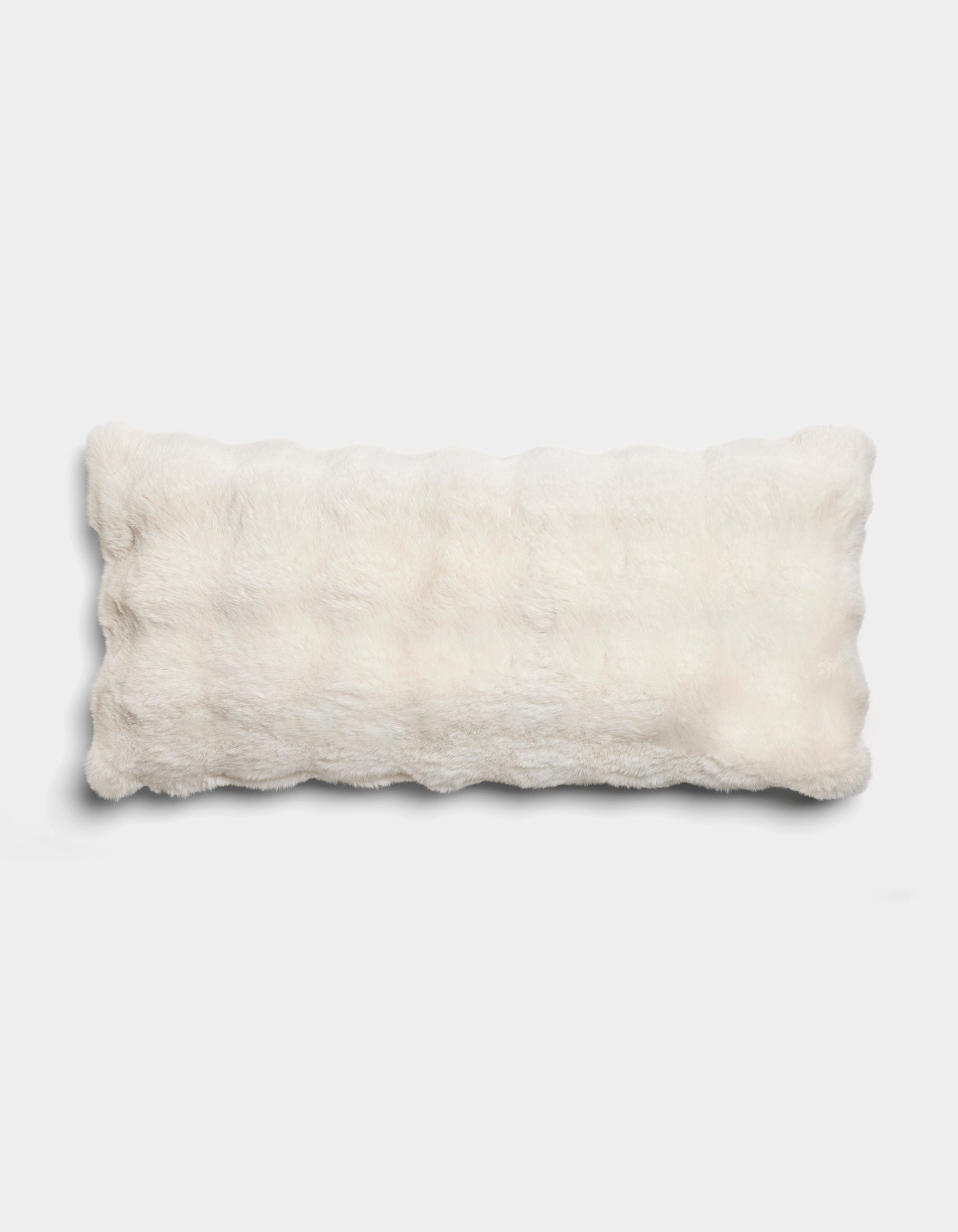 The Bubble Cuddle Pillow by Cozy Earth is a rectangular, fluffy white pillow with a soft, furry texture, displayed on a plain light gray background.