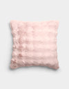 The Bubble Cuddle Pillow by Cozy Earth is a square, pale pink plush pillow with a soft, furry texture and subtle horizontal ridges, shown against a plain light gray background.|Color:Blossom