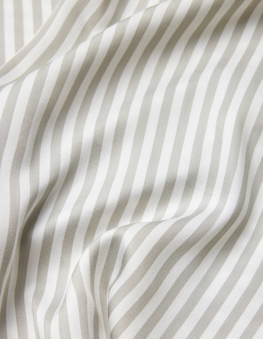 A close-up of the Cozy Earth Bamboo Sheet Set shows soft, white fabric with light gray vertical stripes, gentle folds, and a smooth texture.|Color:Classic Stripe in Laurel