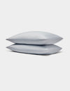 Two light gray Bamboo Jersey Pillowcases by Cozy Earth stacked neatly on each other against a plain white background.|Color:Shore