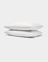 Two Bamboo Jersey Pillowcases by Cozy Earth, in white, stacked neatly against a plain light gray background.|Color:White