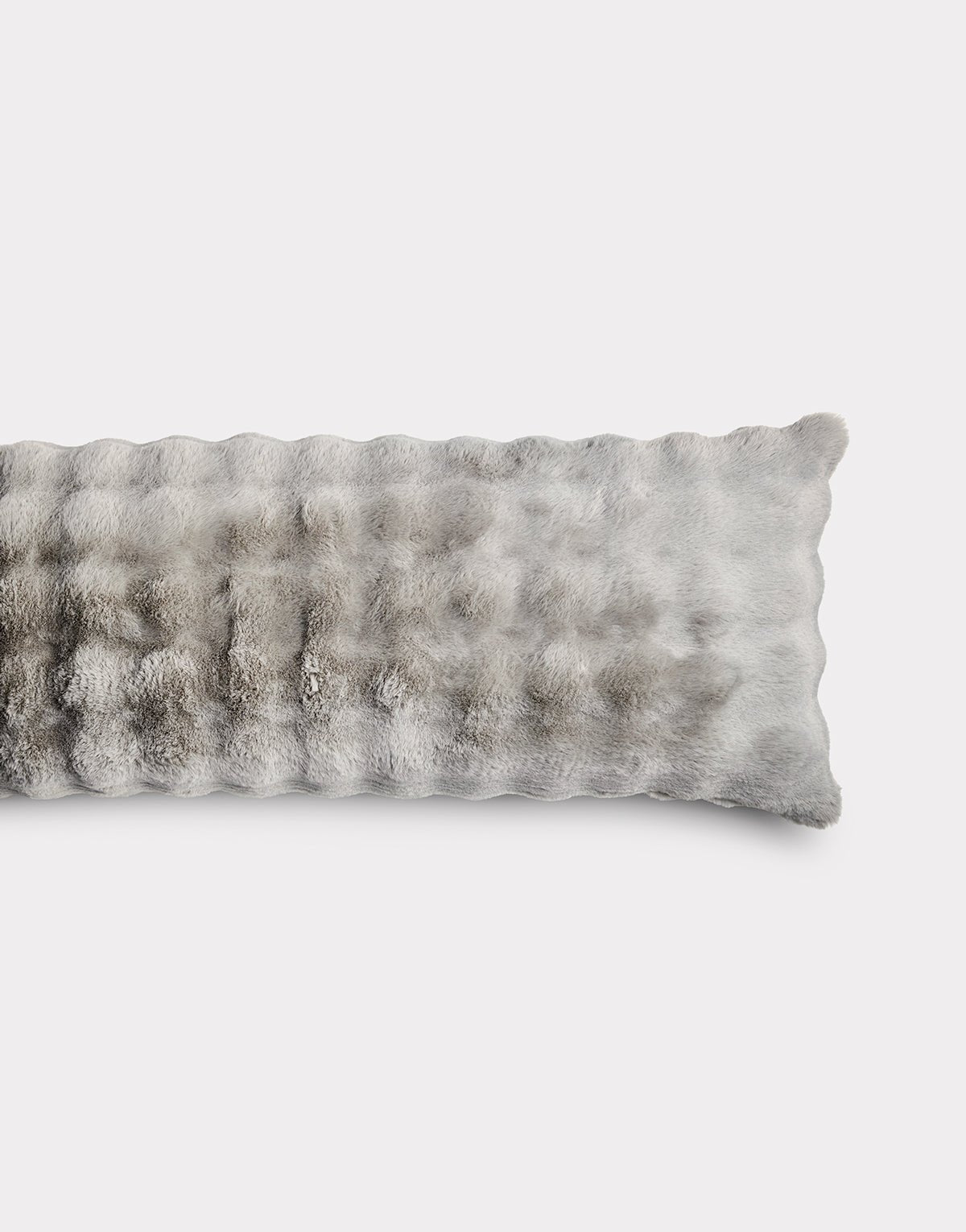 The Bubble Cuddle Pillow by Cozy Earth is a rectangular, grey faux fur pillow with a plush, soft texture. Displayed on a plain white background, only half of the pillow appears in the image.|Color:Light Grey |Size:Body - 20" x 54"