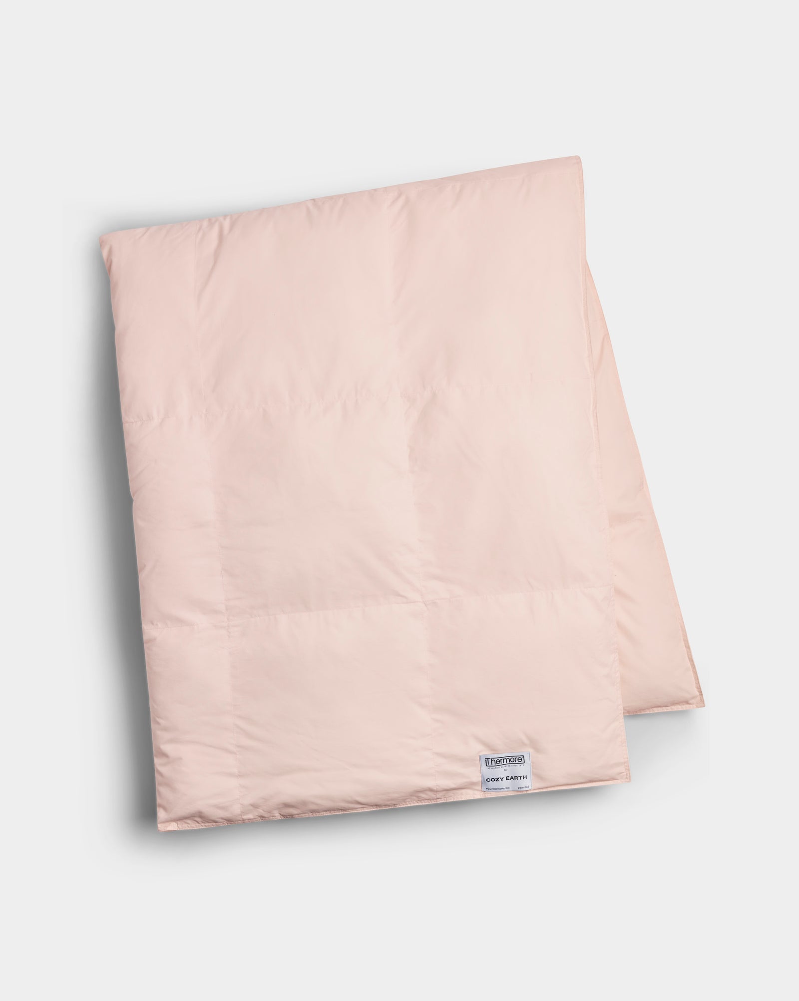 The Cozy Earth Down Alternative Throw, shown folded in light pink with a small white label near the edge, is displayed on a plain white background.