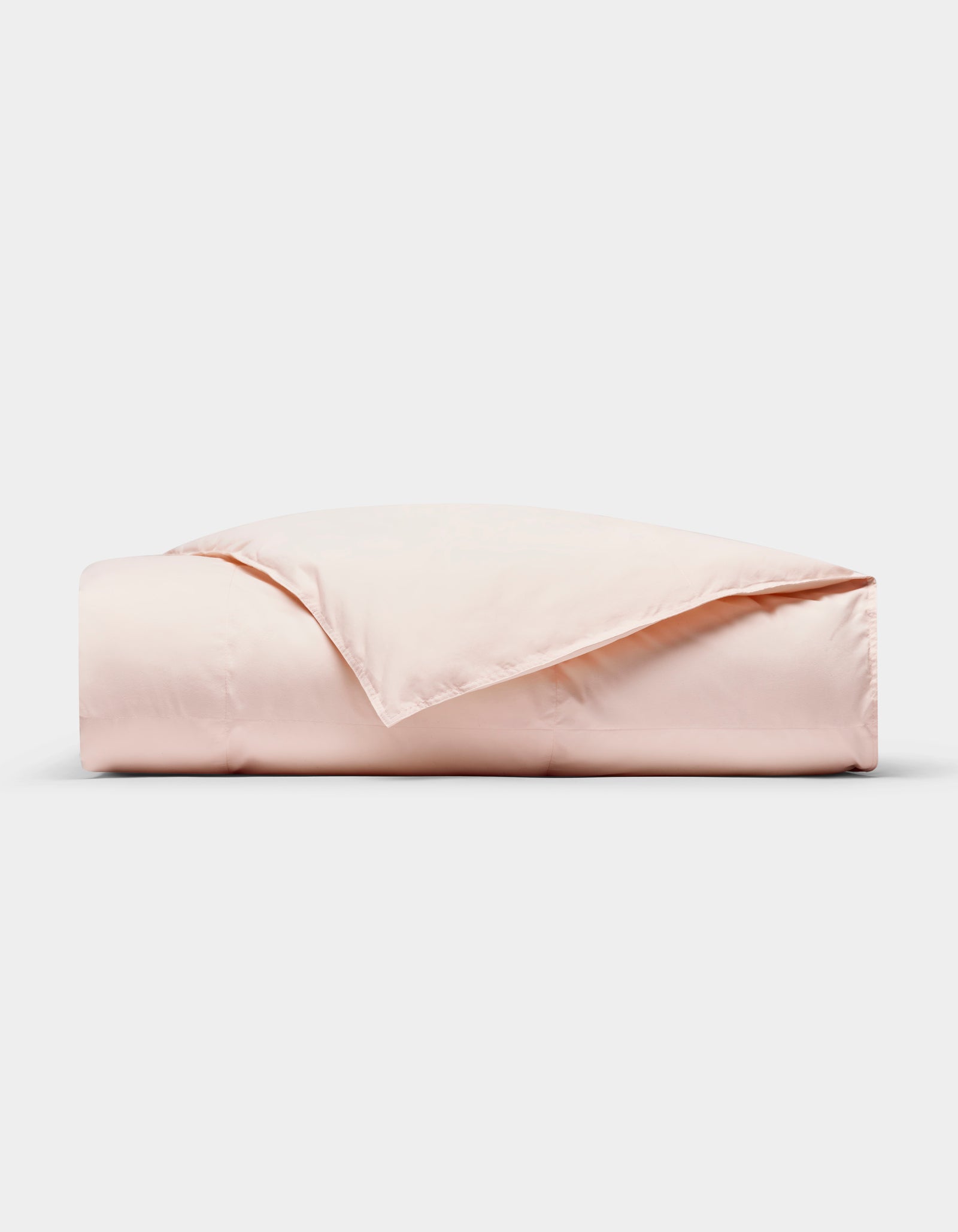 The Cozy Earth Down Alternative Throw in light pink is neatly folded against a white background, with one corner turned back to reveal its soft texture.