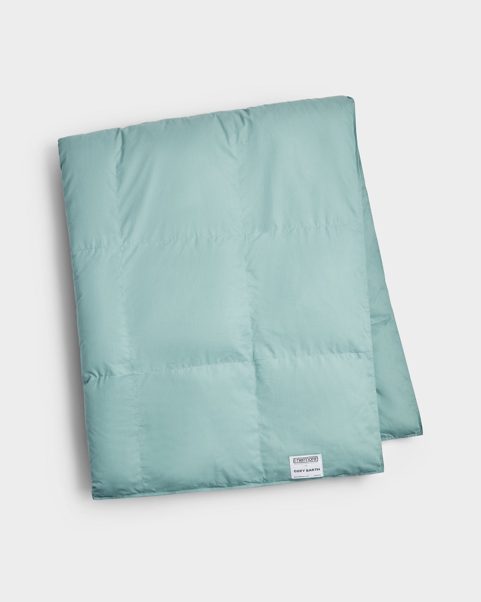 A neatly folded light teal Down Alternative Throw by Cozy Earth, featuring a small white label in the corner. The blanket looks soft and plush, displayed against a plain white background.