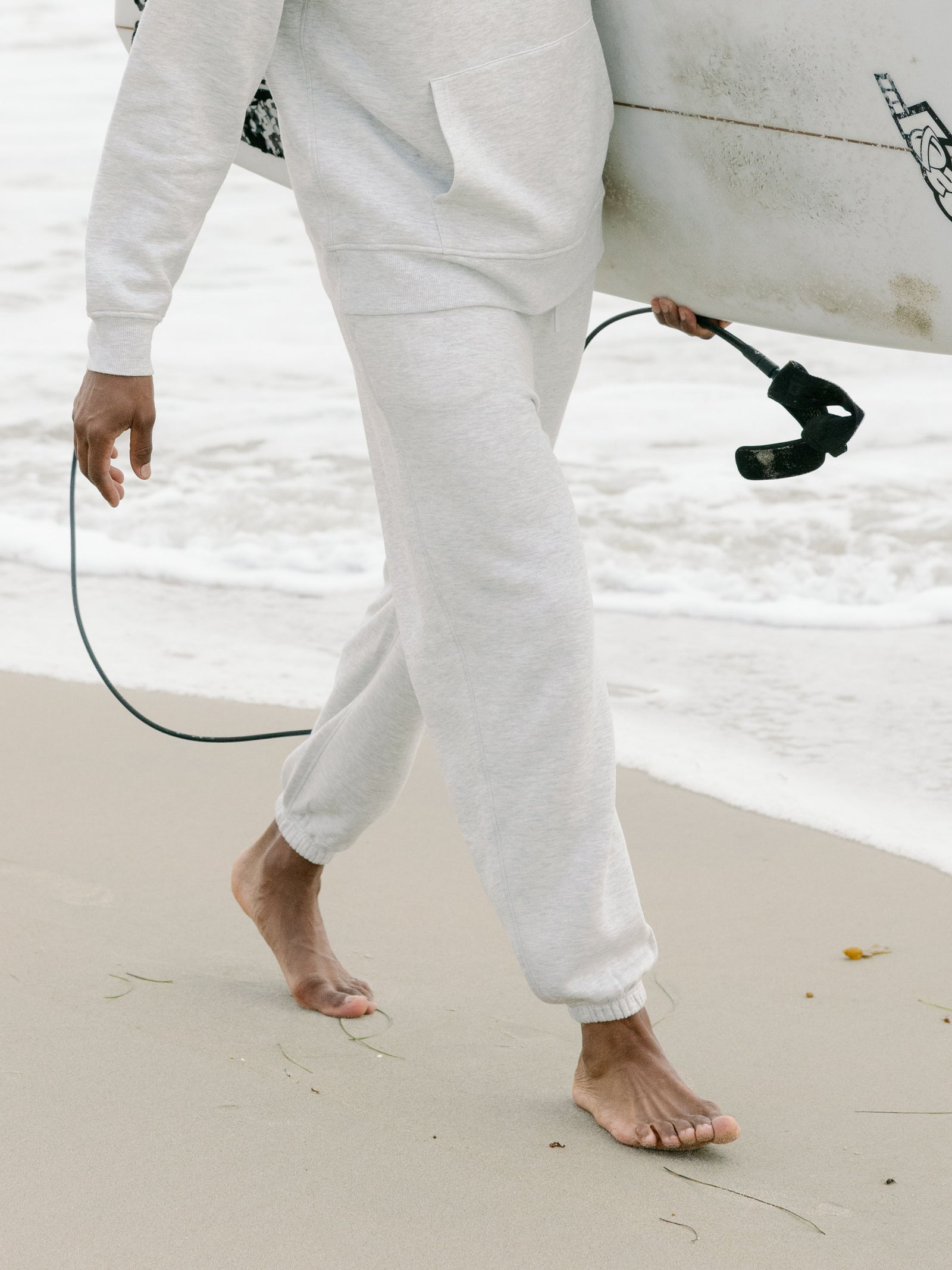 Waist down of man wearing heather grey cityscape sweats on beach 