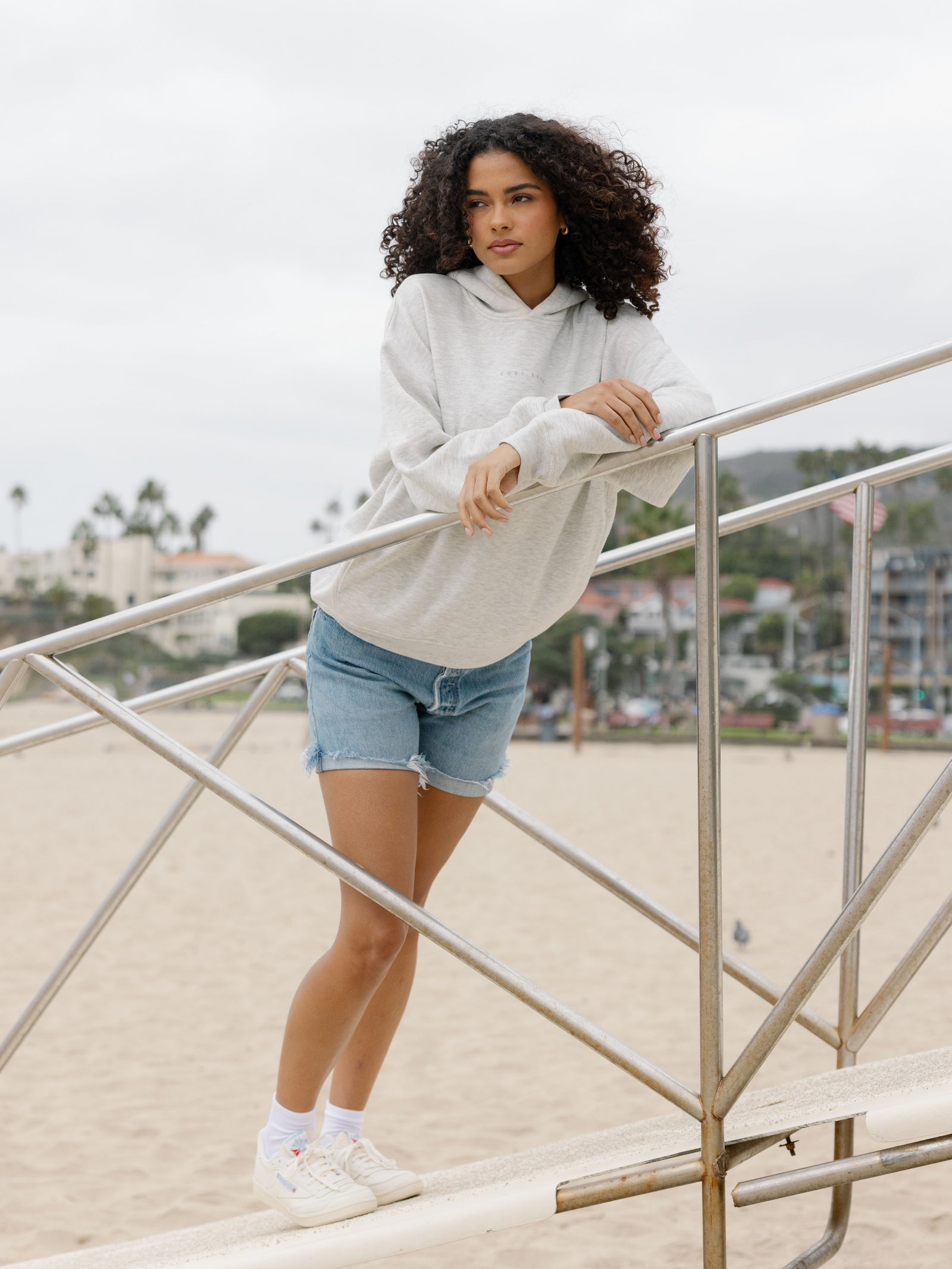 Heather GreyWoman wearing jorts and heather grey cityscape hoodie on the beach 