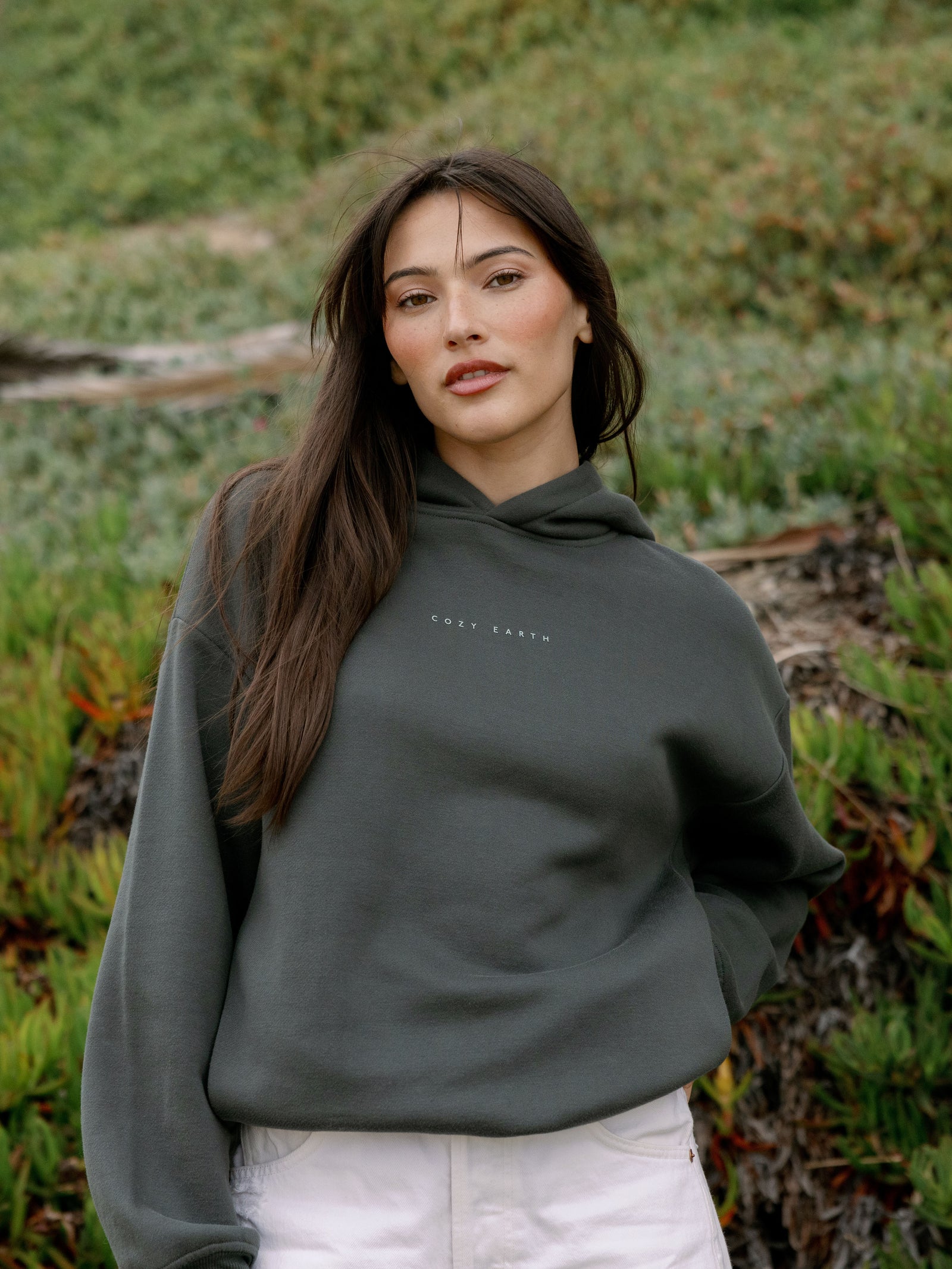 Woman wearing storm cityscape hoodie with grass behind her 
