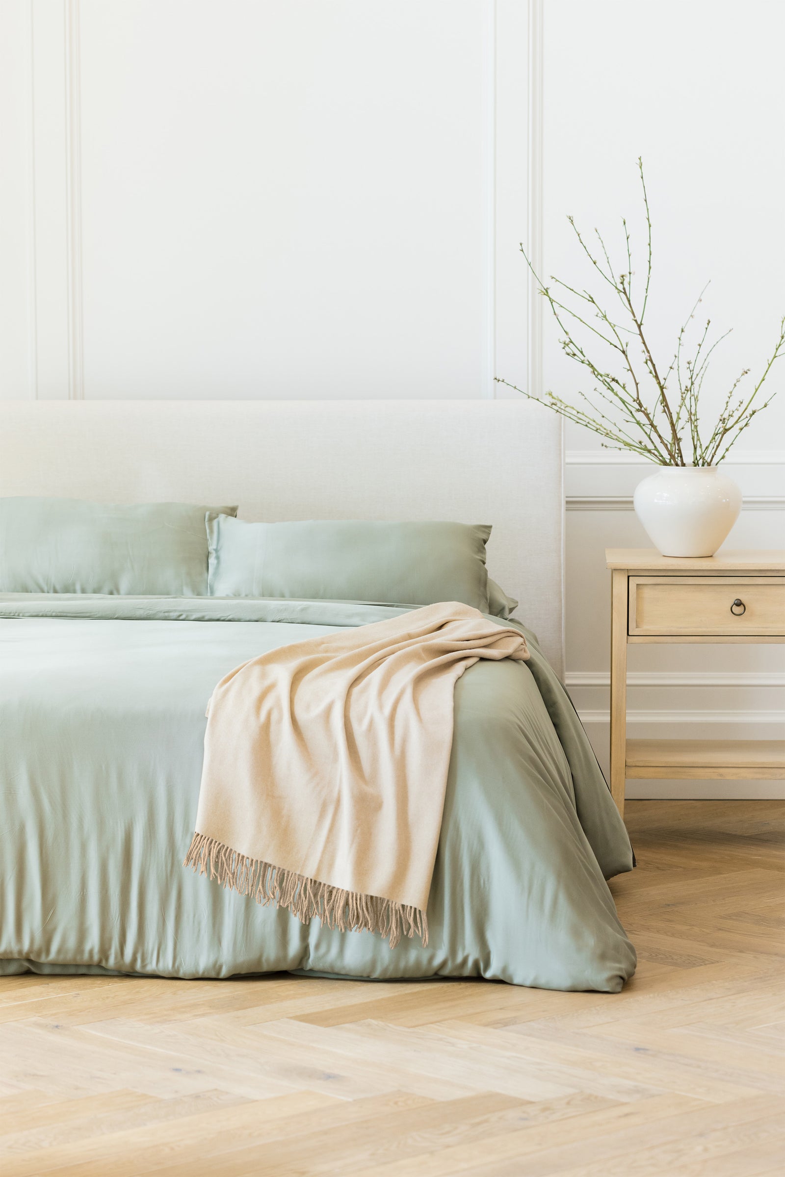 Dune tassel throw draped over bed with sage bedding 