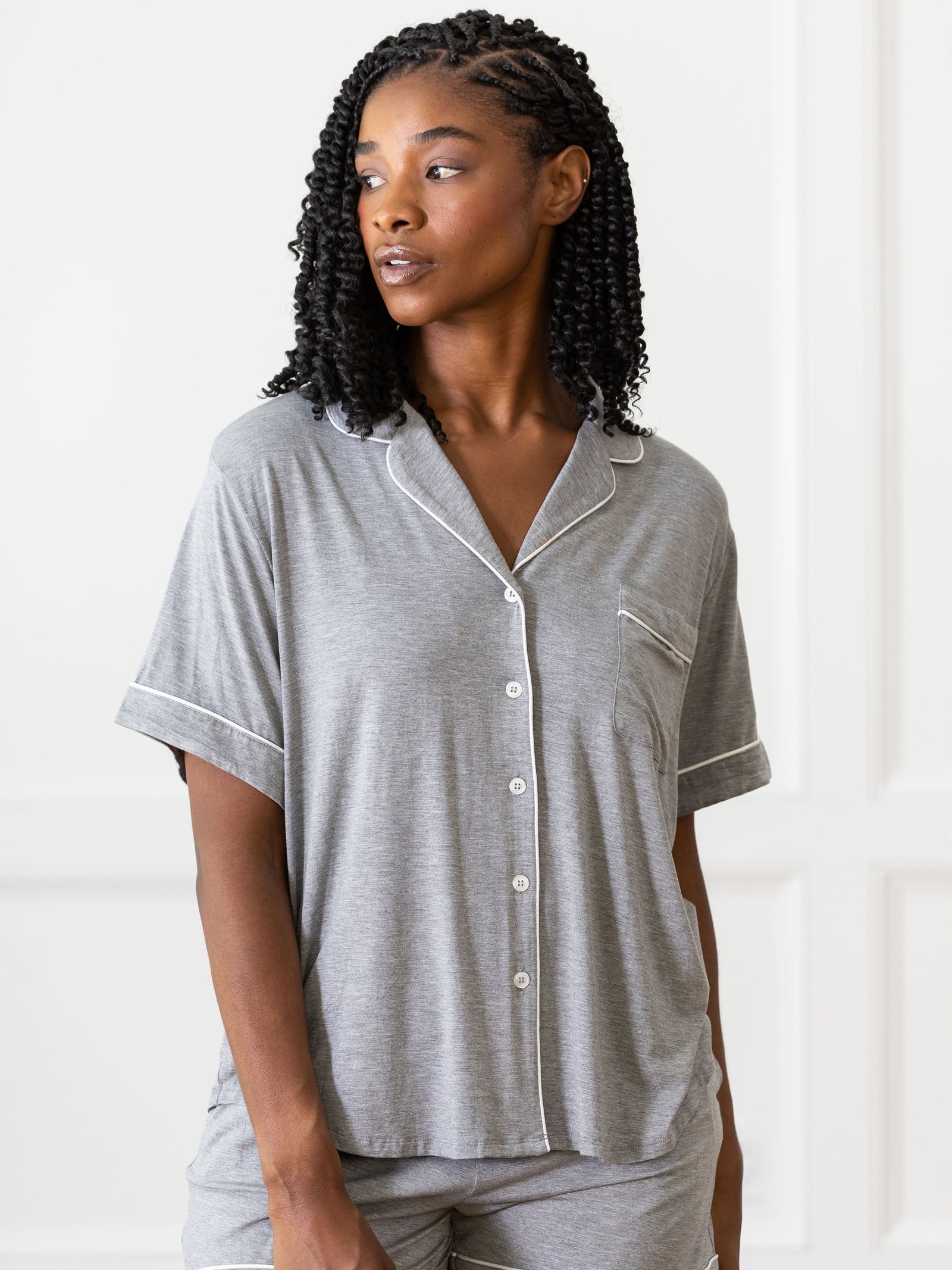 Grey Short Sleeve Pajama Set modeled by a woman. The photo was taken in a light setting, showing off the colors and lines of the pajamas.