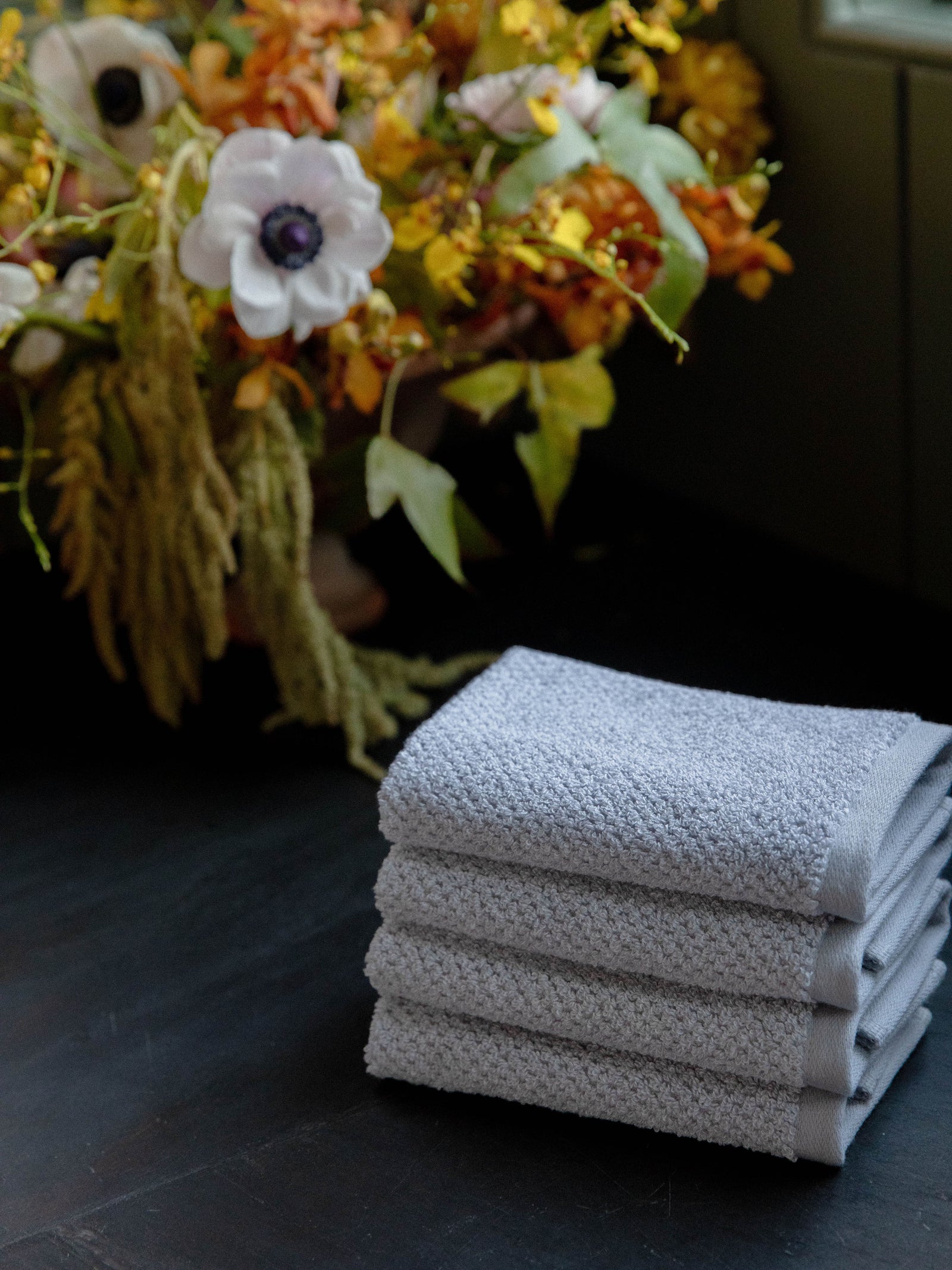 Nantucket Wash Cloths in the color Heathered Harbor Mist. Photo of Nantucket Wash Cloths taken with the Wash Cloths resting on a countertop in a bathroom. 