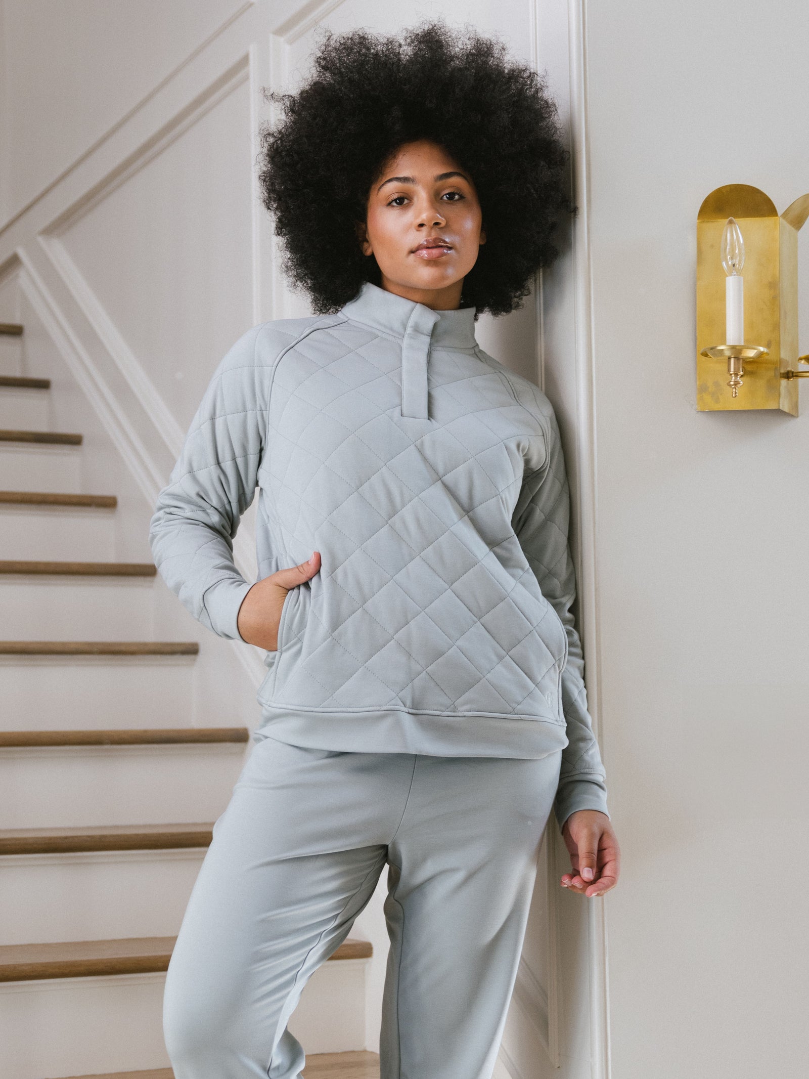 Woman wearing a white Cozy Earth Brushed Bamboo Quilted Pullover against a staircase background