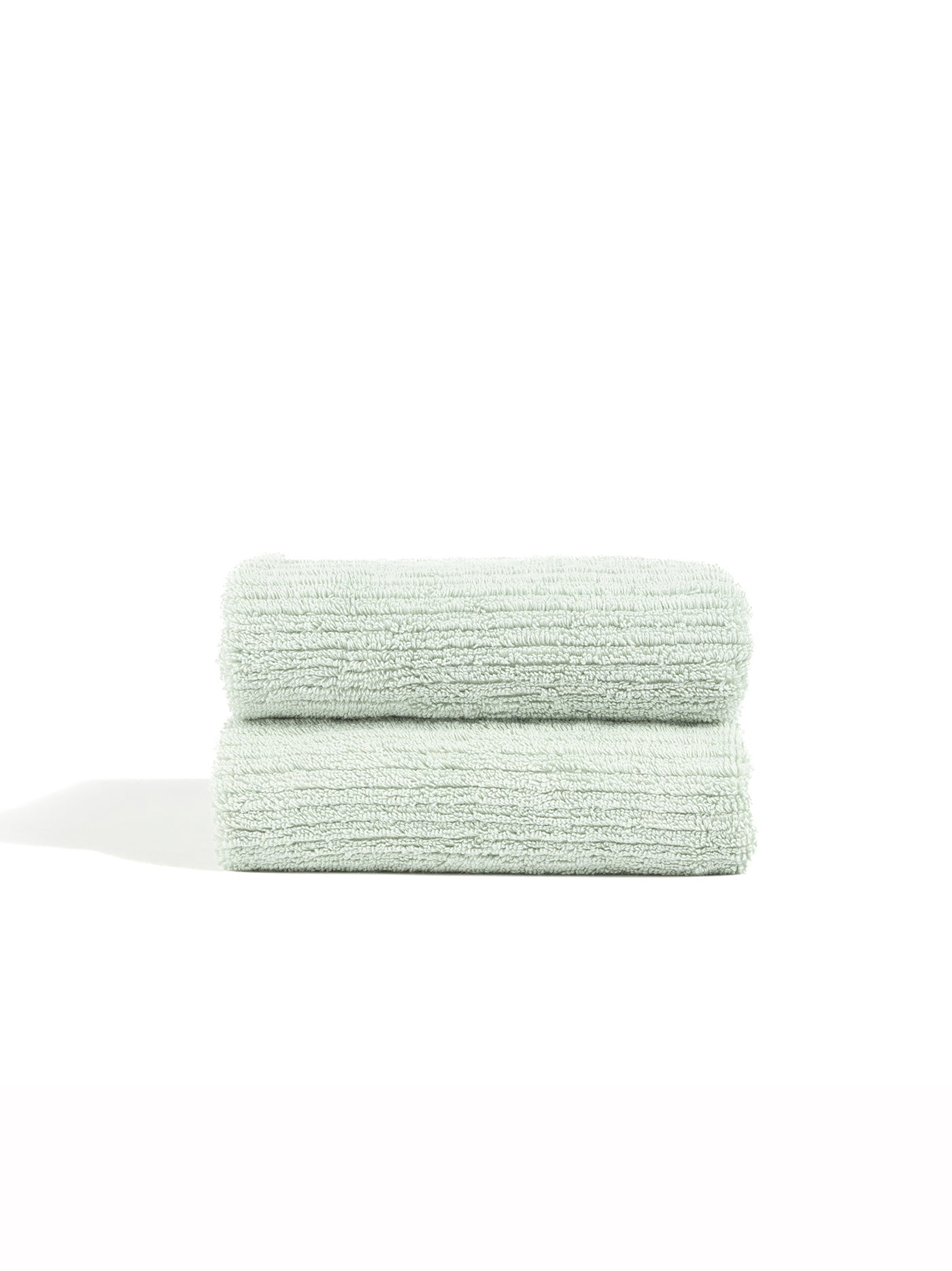 Two Ribbed Terry Hand Towels by Cozy Earth, neatly folded and stacked, are displayed against a plain white background.|Color:Laurel