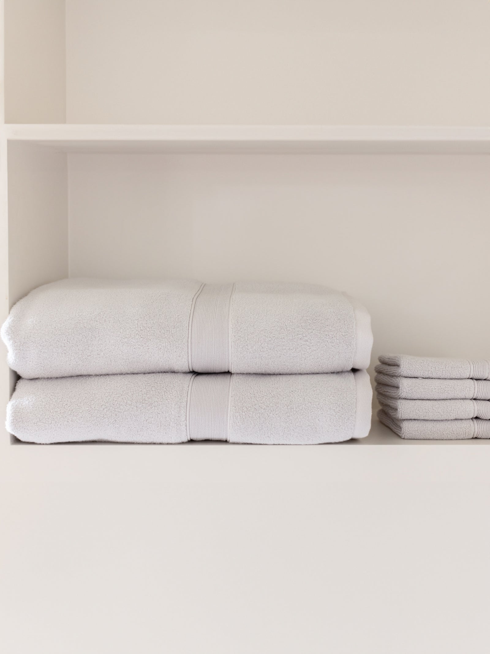 Light grey luxe bath sheets and washcloths on shelf 