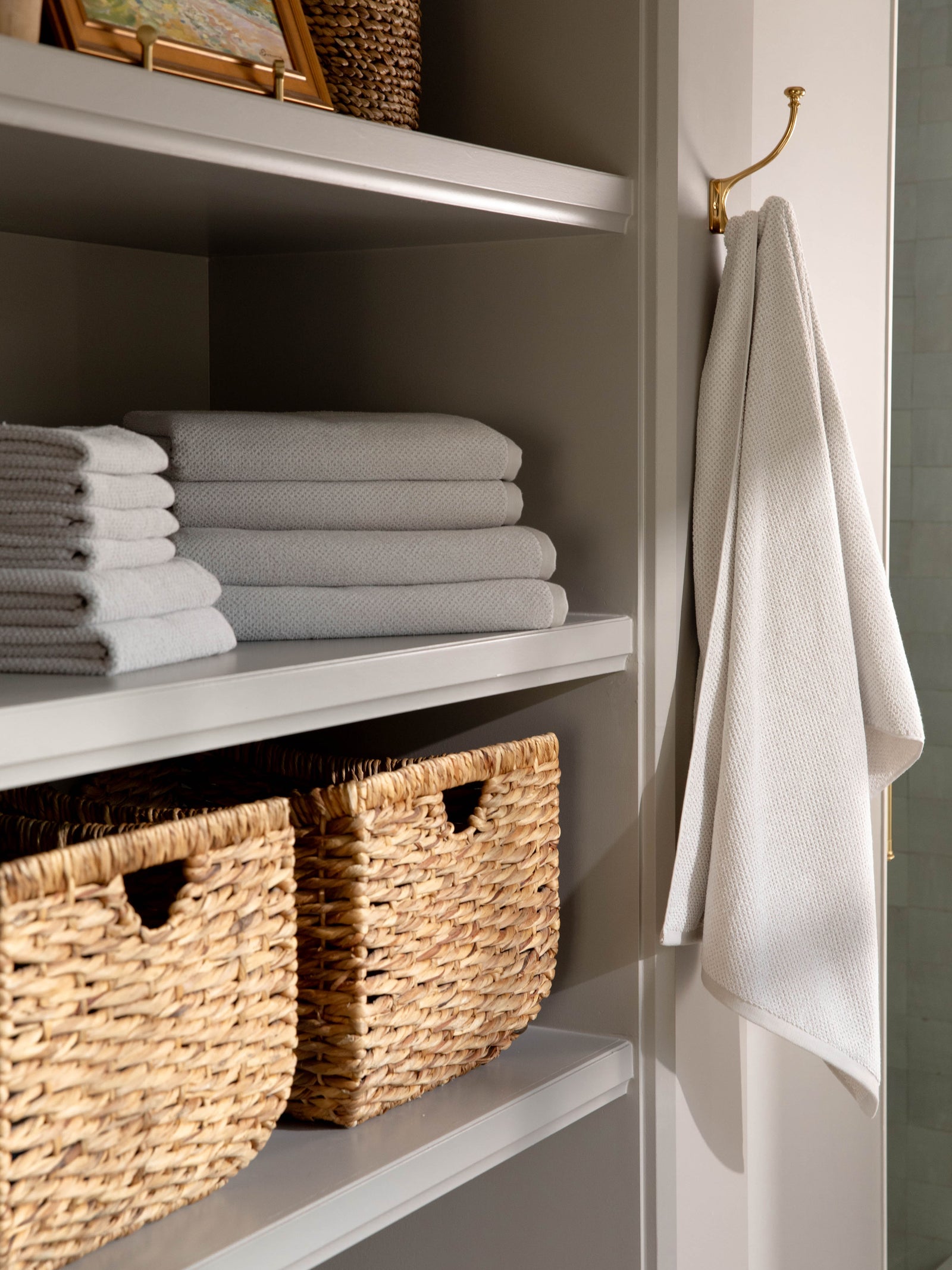 Complete Nantucket Bath Bundle in the color Heathered Light Grey. Photo of Complete Nantucket Bath Bundle taken as the towels rest on a shelf in a bathroom. 