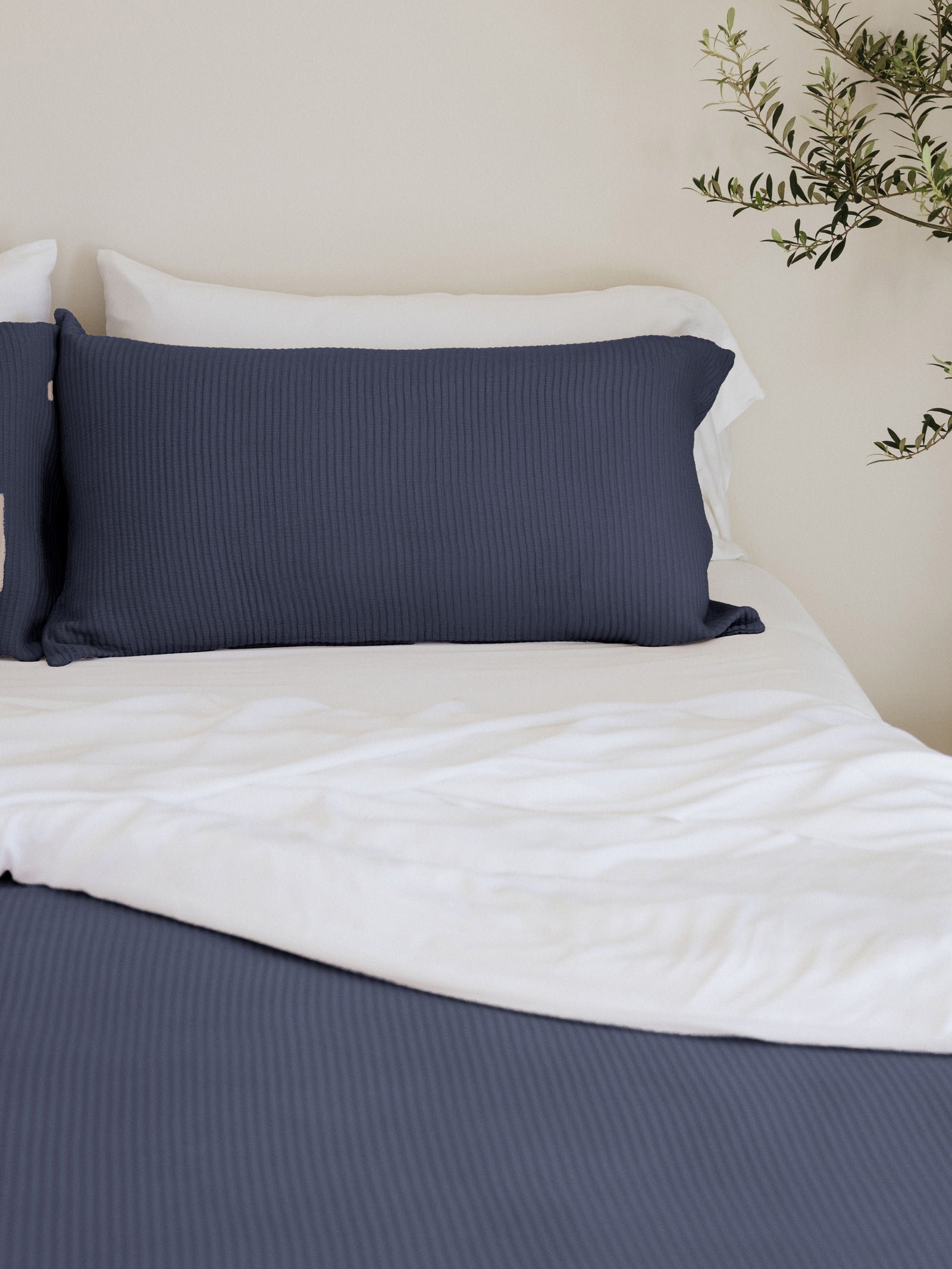 Navy coverlet shams and quilt on white bed 