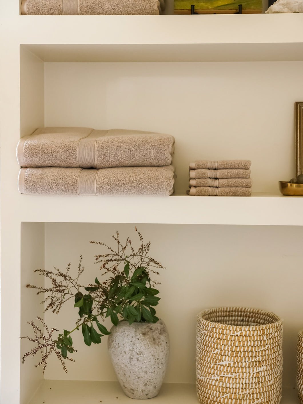 Sand luxe bath towels and washcloths folded on shelf 