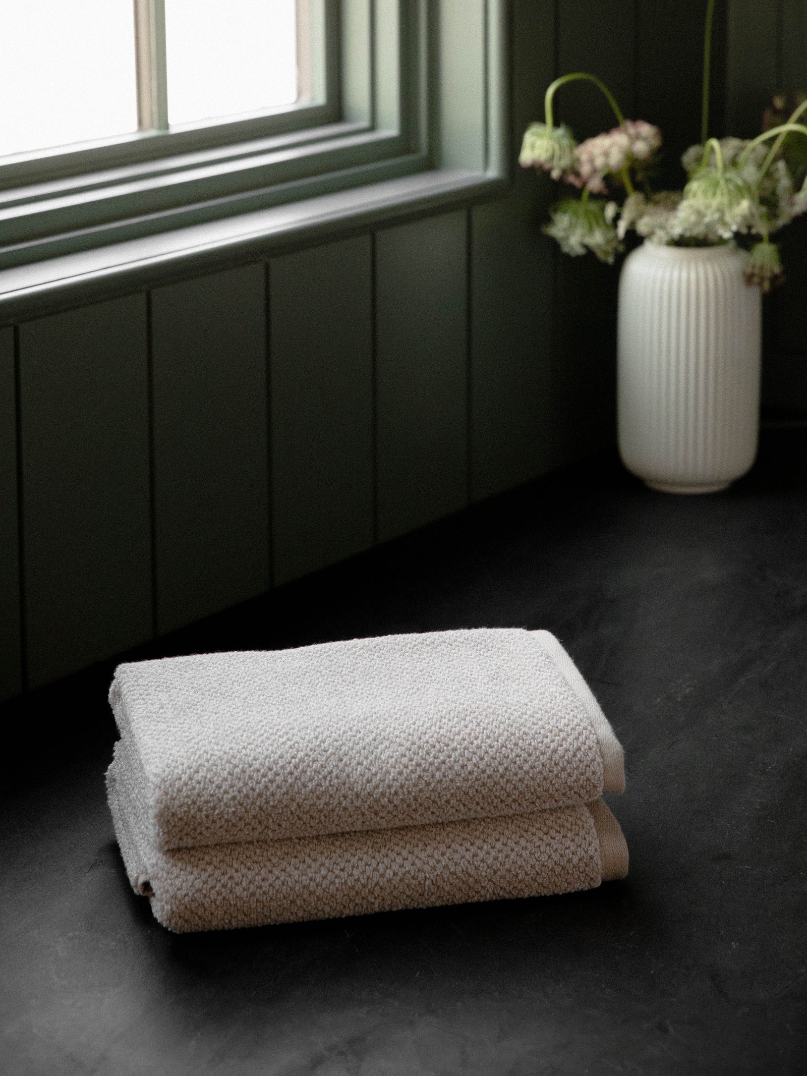 Nantucket Hand Towels in the color Heathered Sand. Photo of Nantucket Hand Towels taken with the Hand Towels resting on a countertop in a bathroom. 