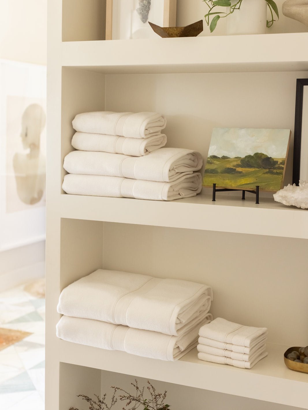 Collection of seashell luxe bath towels folded on shelves 