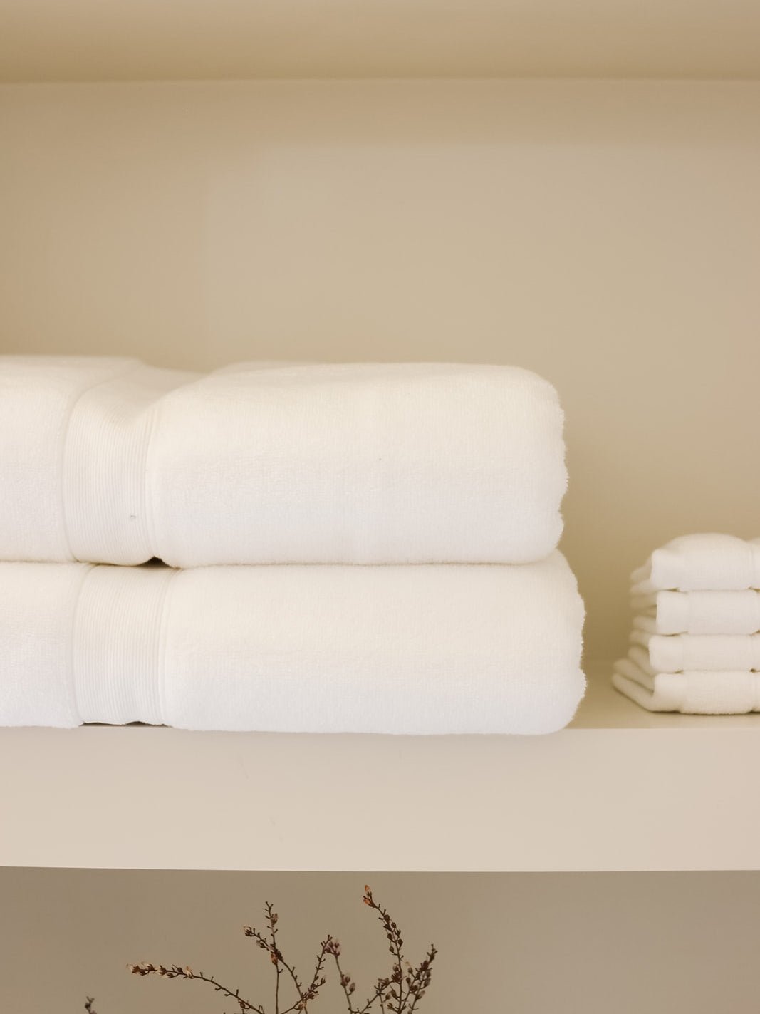 White luxe bath towels and washcloths folded on shelf 