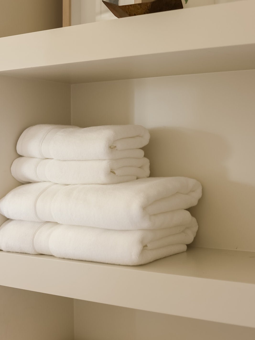 White luxe bath towels and hand towels folded on shelf 