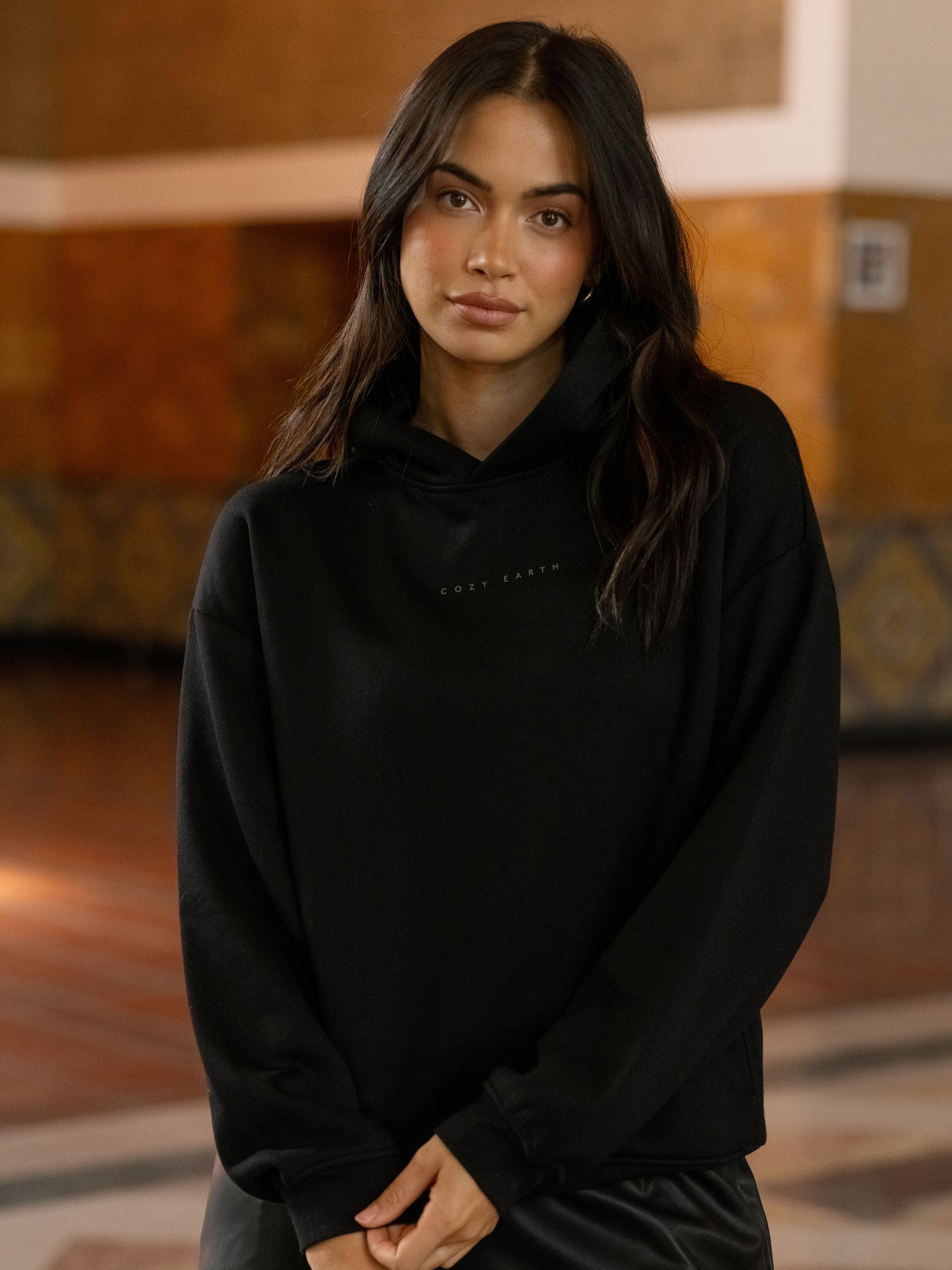 Woman wearing black cityscape hoodie inside of building 