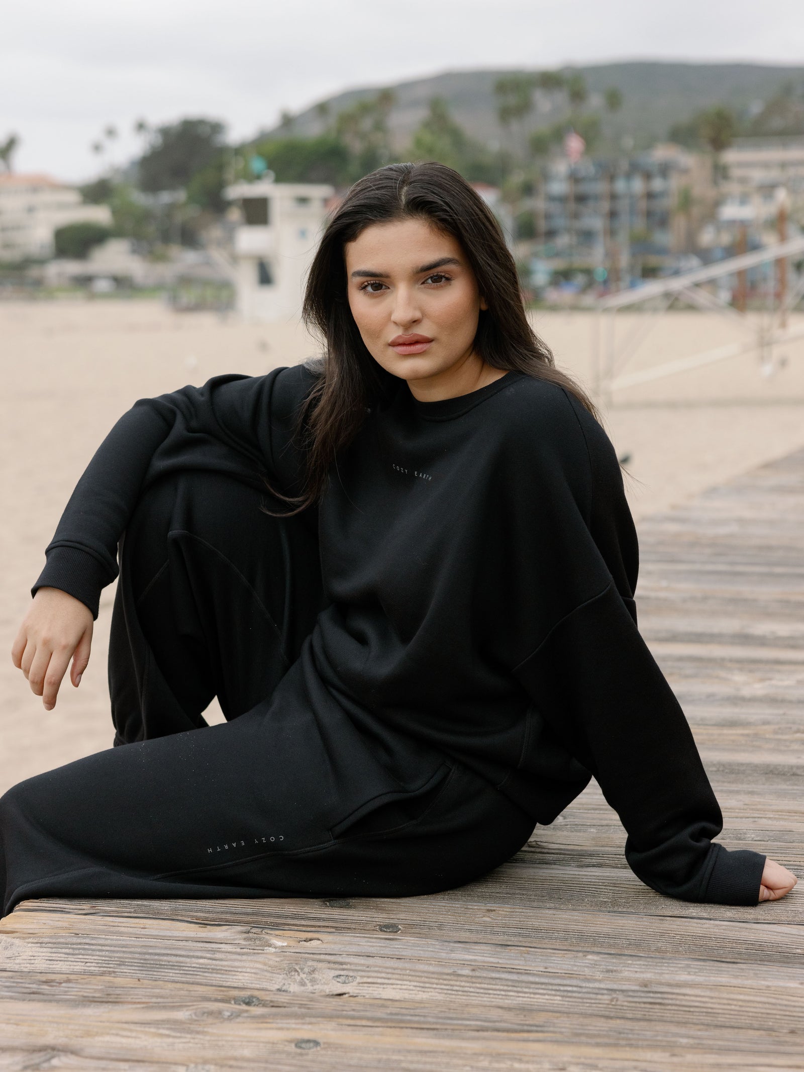 Woman sitting on boardwalk in black cityscape set