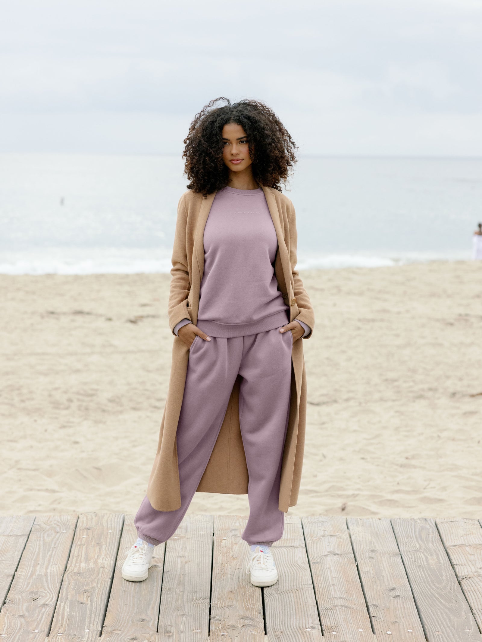 Woman wearing dusty orchid cityscape set on boardwalk with coat over it