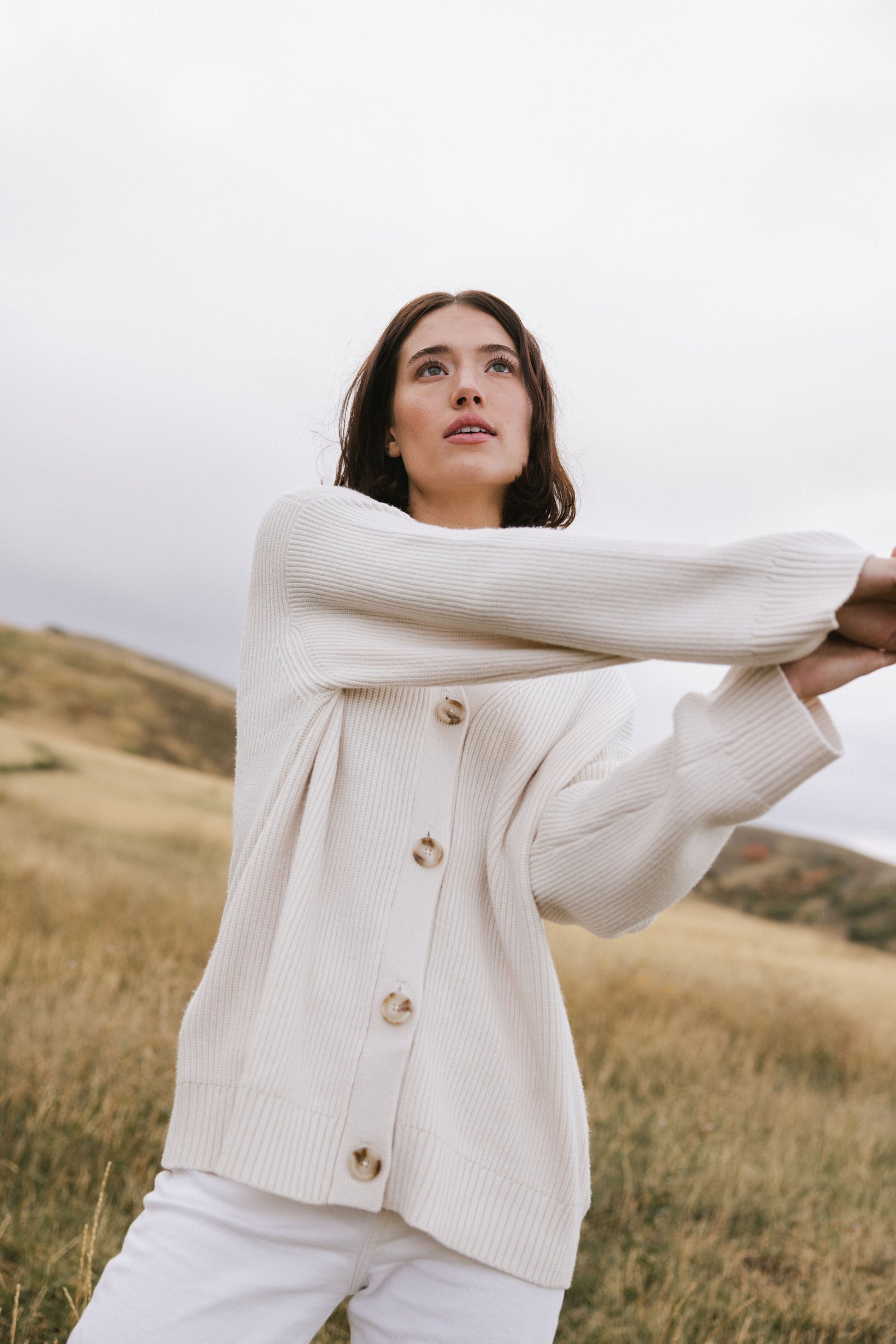 A woman wearing Cozy Earth Classic Cardigan in white stands in a field