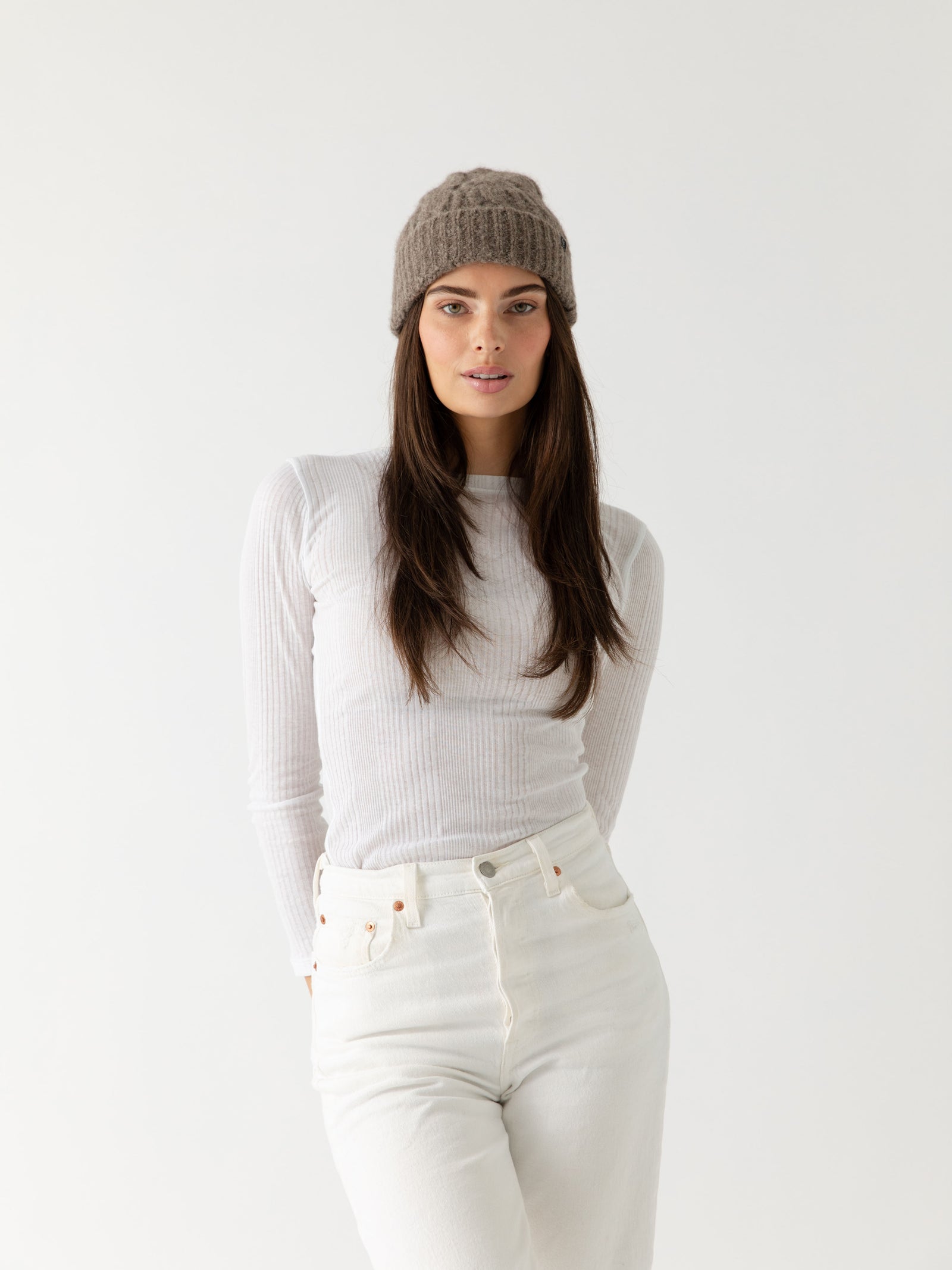 Woman wearing a gray Cozy Earth Cable Knit Beanie and scarf with a white background.