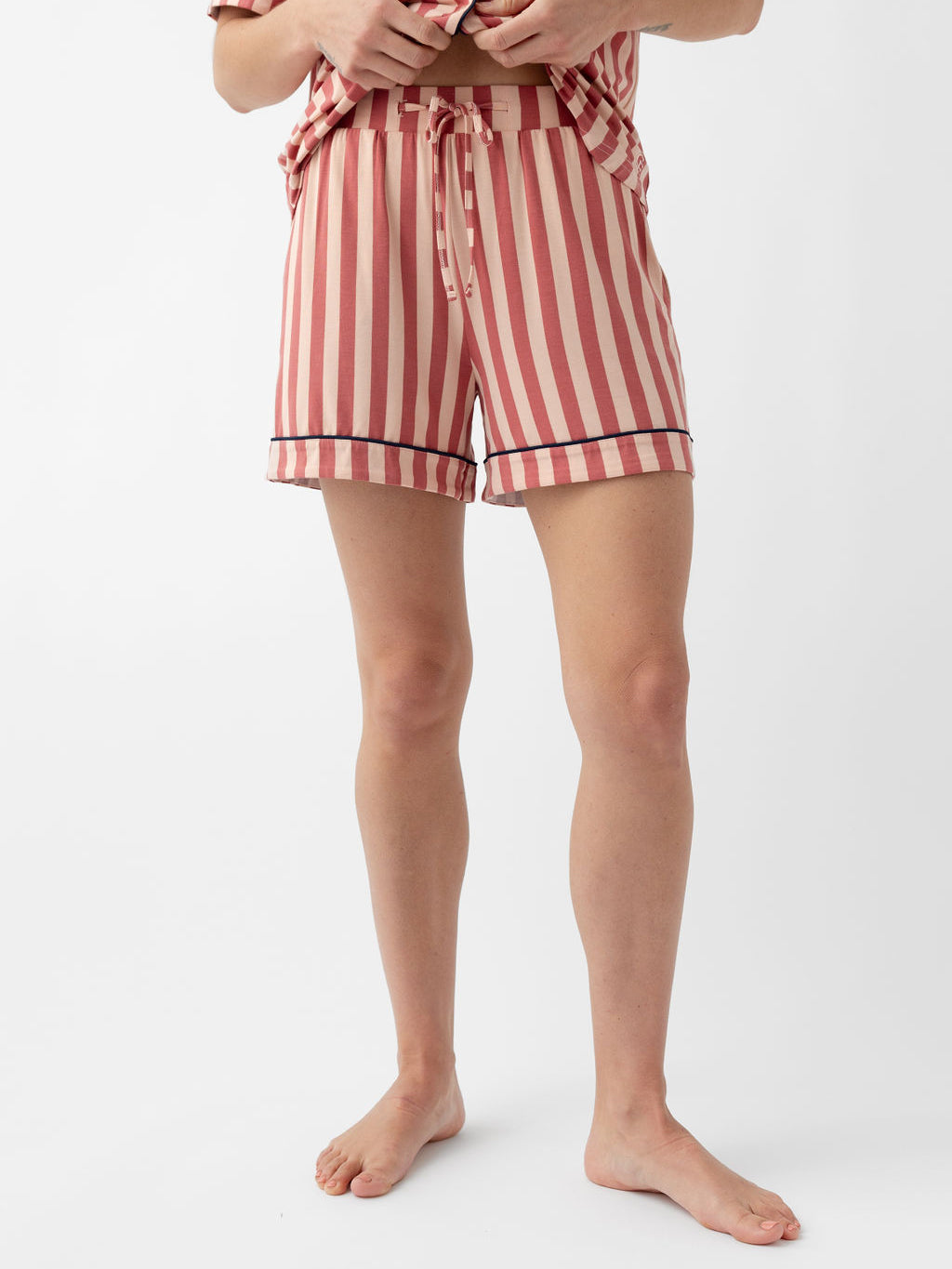 Woman wearing blush stripe pajama shorts with white background