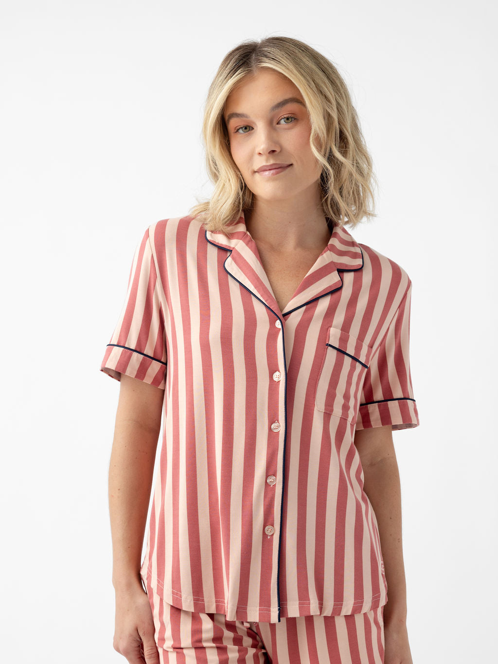 Woman wearing blush stripe short sleeve pajama top with white background