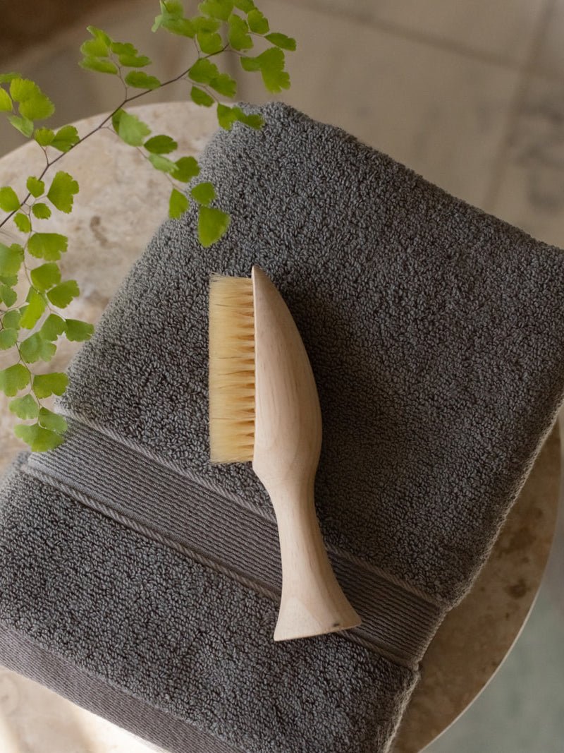 Charcoal luxe hand towels on small table with brush 
