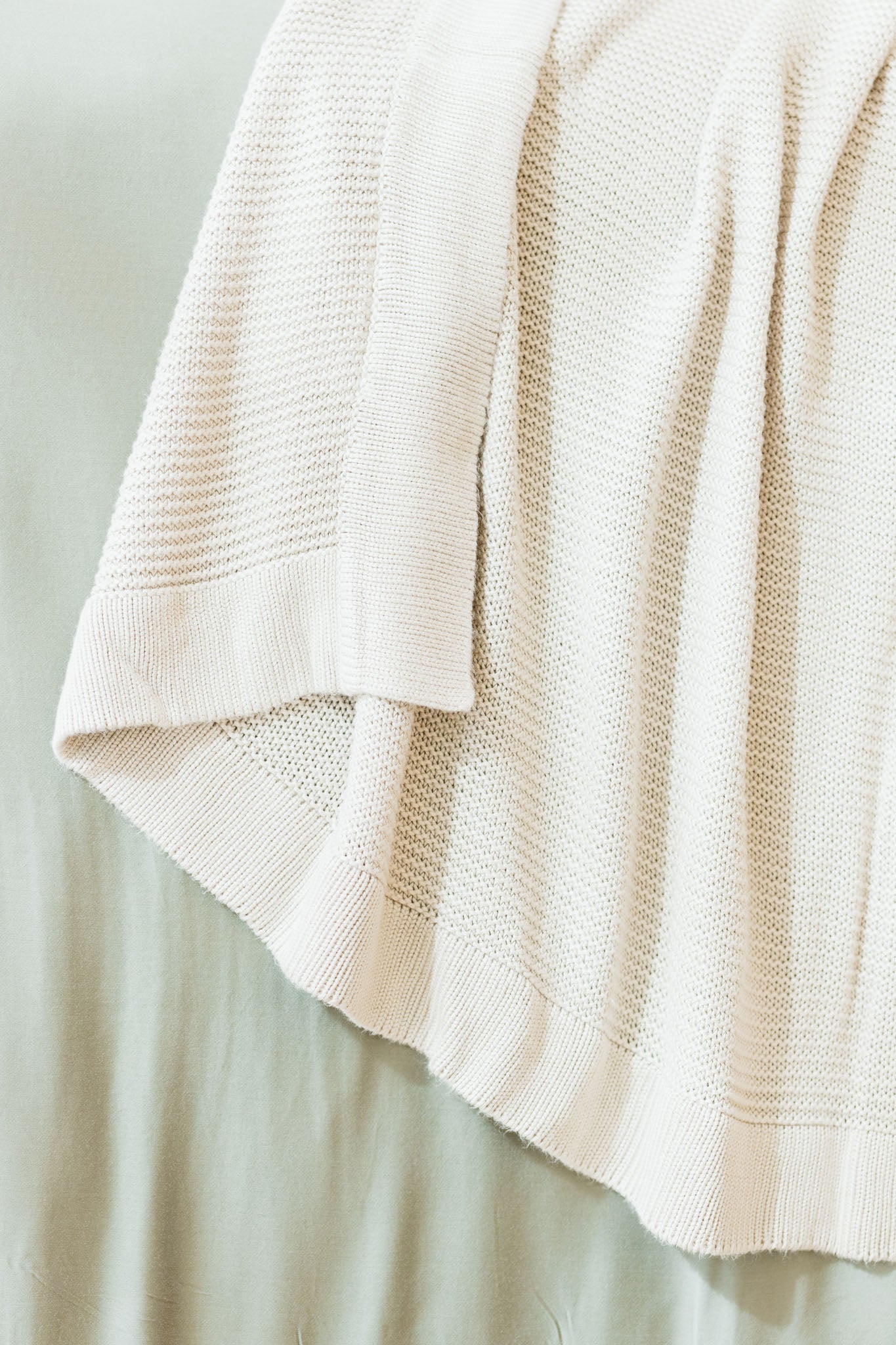 Driftwood cloud knit blanket close up draped over bed |Color:Driftwood