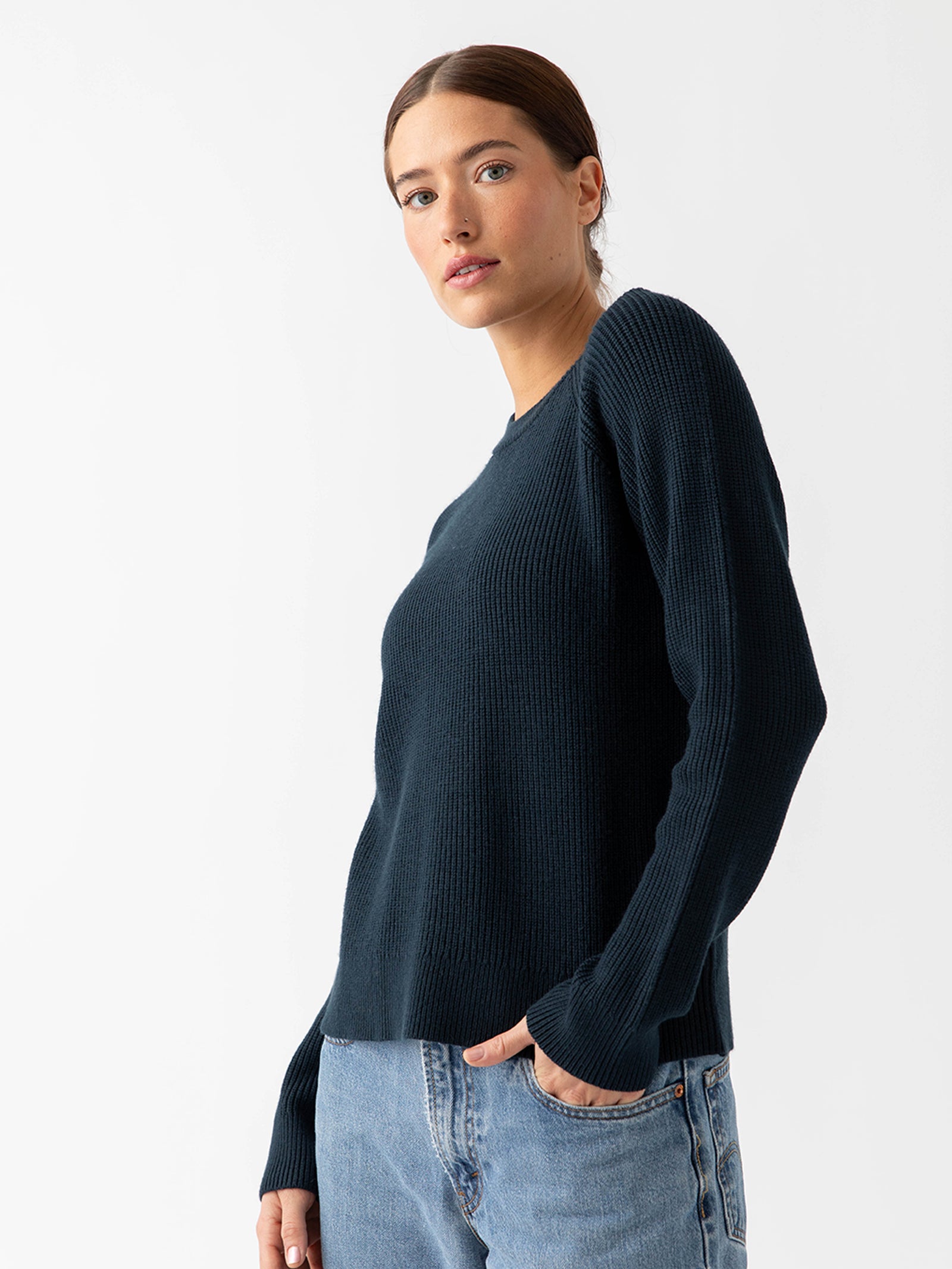 Woman waist up wearing eclipse classic crewneck and jeans with white background