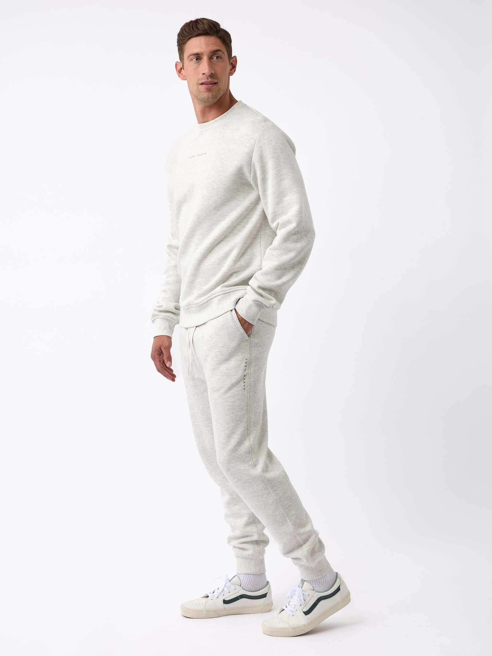 A person stands against a white background, dressed in the Men's CityScape Jogger by Cozy Earth, paired with white sneakers. The outfit exudes a casual and comfortable vibe.