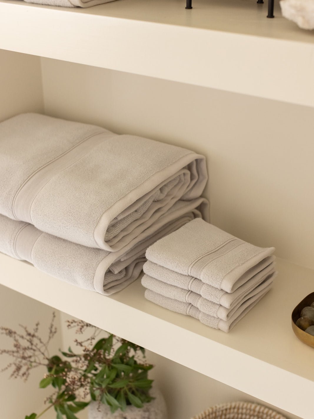 Light grey luxe towels and washcloths folded on shelf 