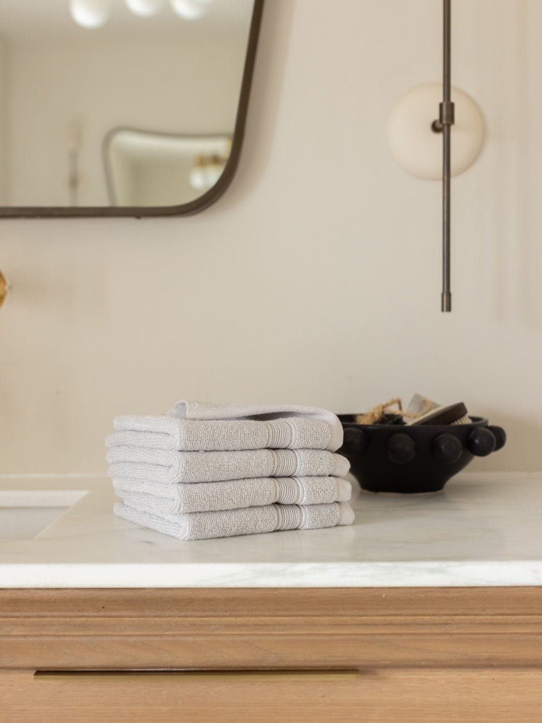 Light grey washcloths folded on bathroom counter 