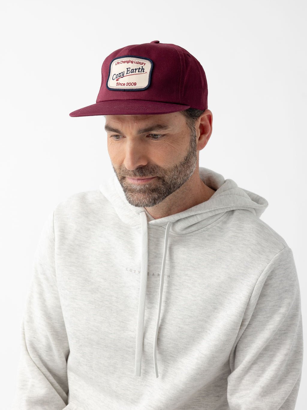 Man looking down wearing maroon heritage snapback 