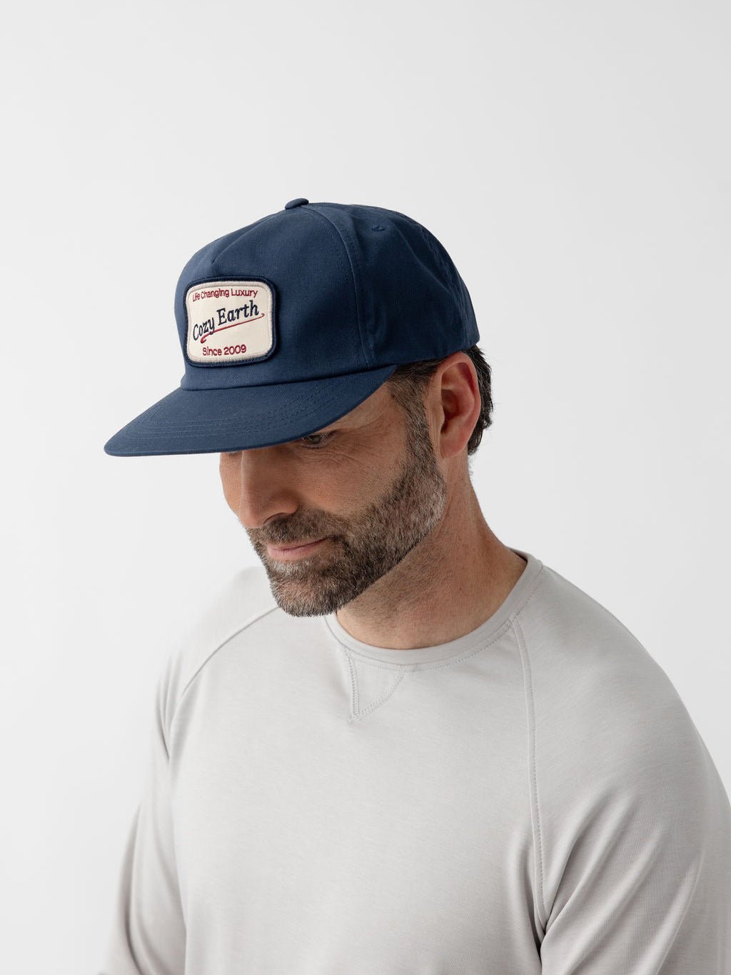 Man wearing navy heritage snapback looking down 