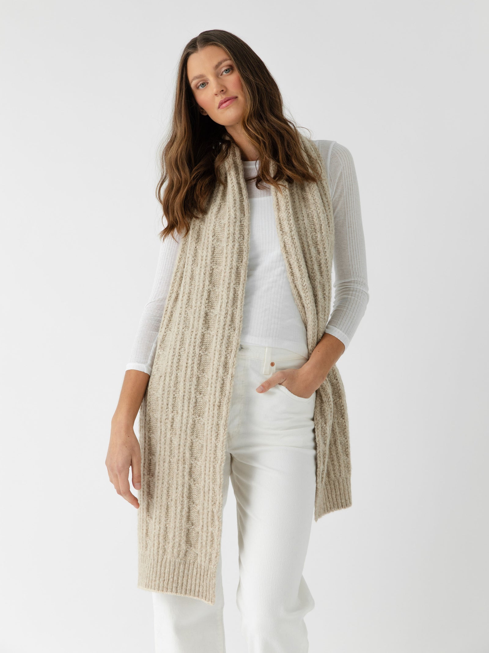 Woman wearing a brown knit cardigan, Cozy Earth Cable Knit Scarf on a white background.
