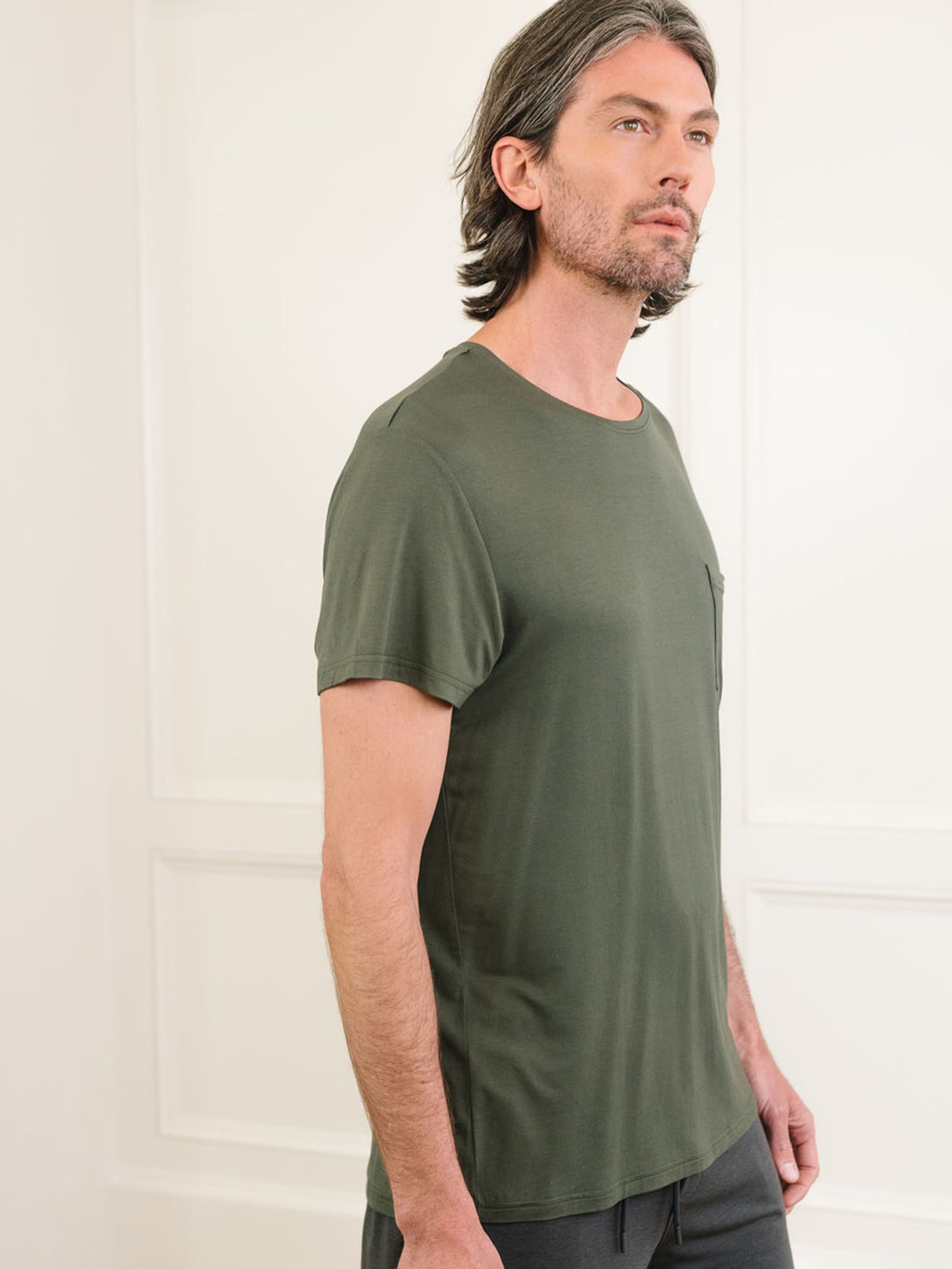 Olive Men's Stretch-Knit Bamboo Lounge Tee. A man is wearing the lounge tee in a well lit home.