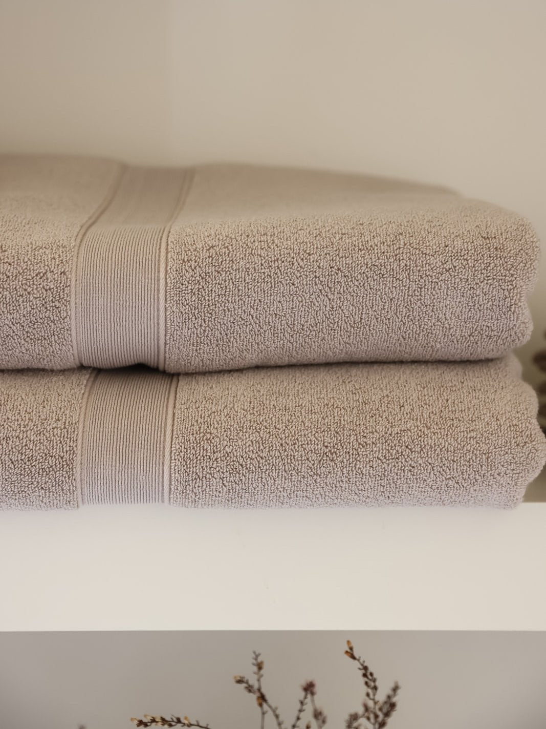 Close up of folded sand luxe bath towels on shelf 