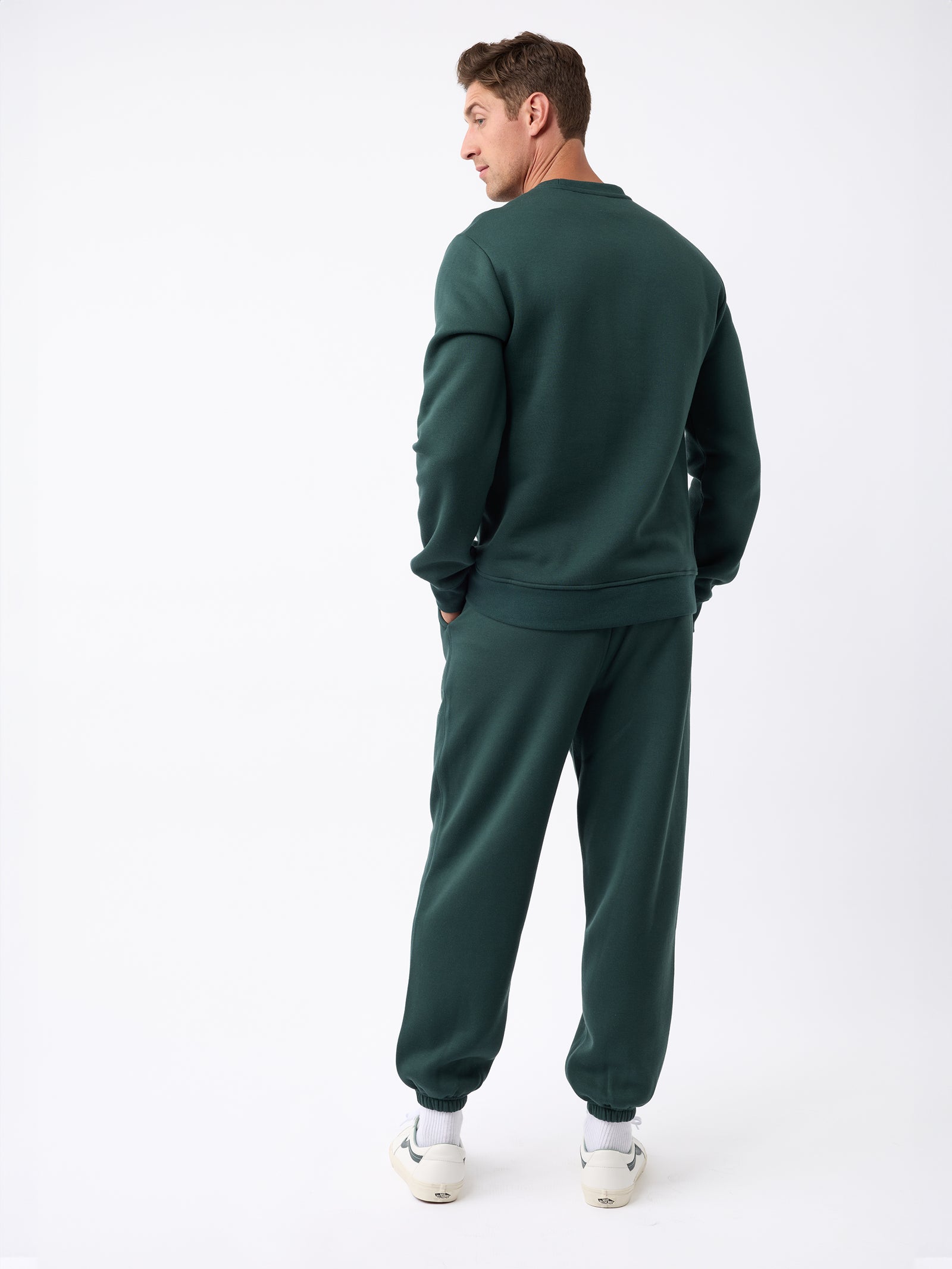 A person wearing the Cozy Earth Men's CityScape Sweatpant and white sneakers stands facing away, looking over their shoulder against a plain white background, which highlights the clothing.