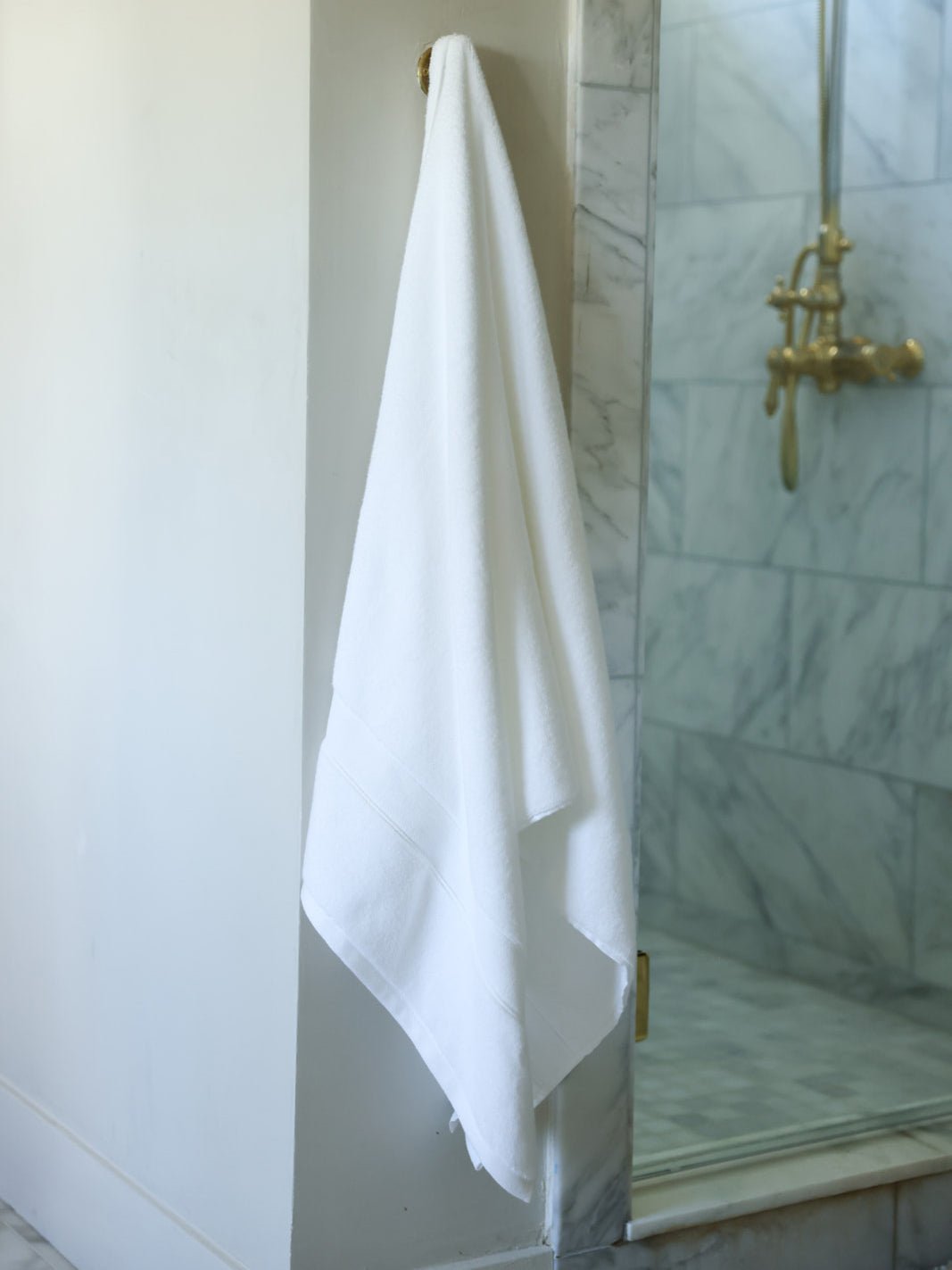 White luxe bath sheet hanging next to shower 
