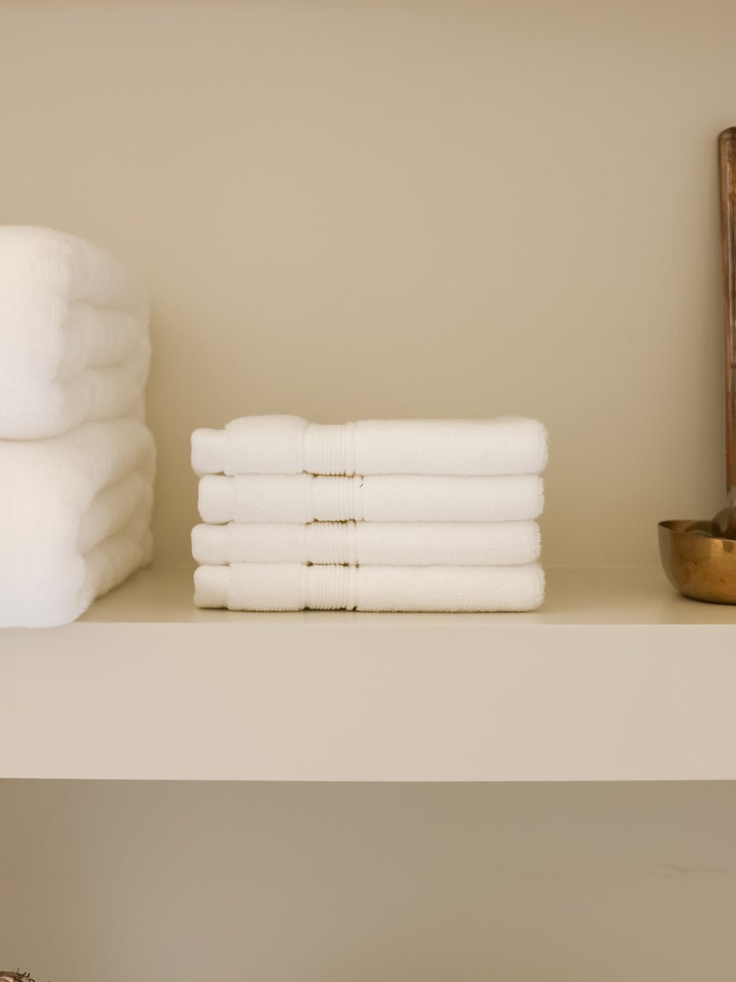White luxe washcloths folded on shelf 
