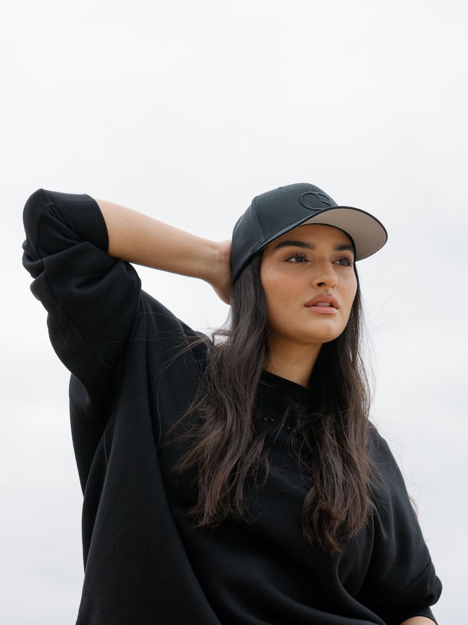 Woman wearing a black cap with a CE logo on a light gray background