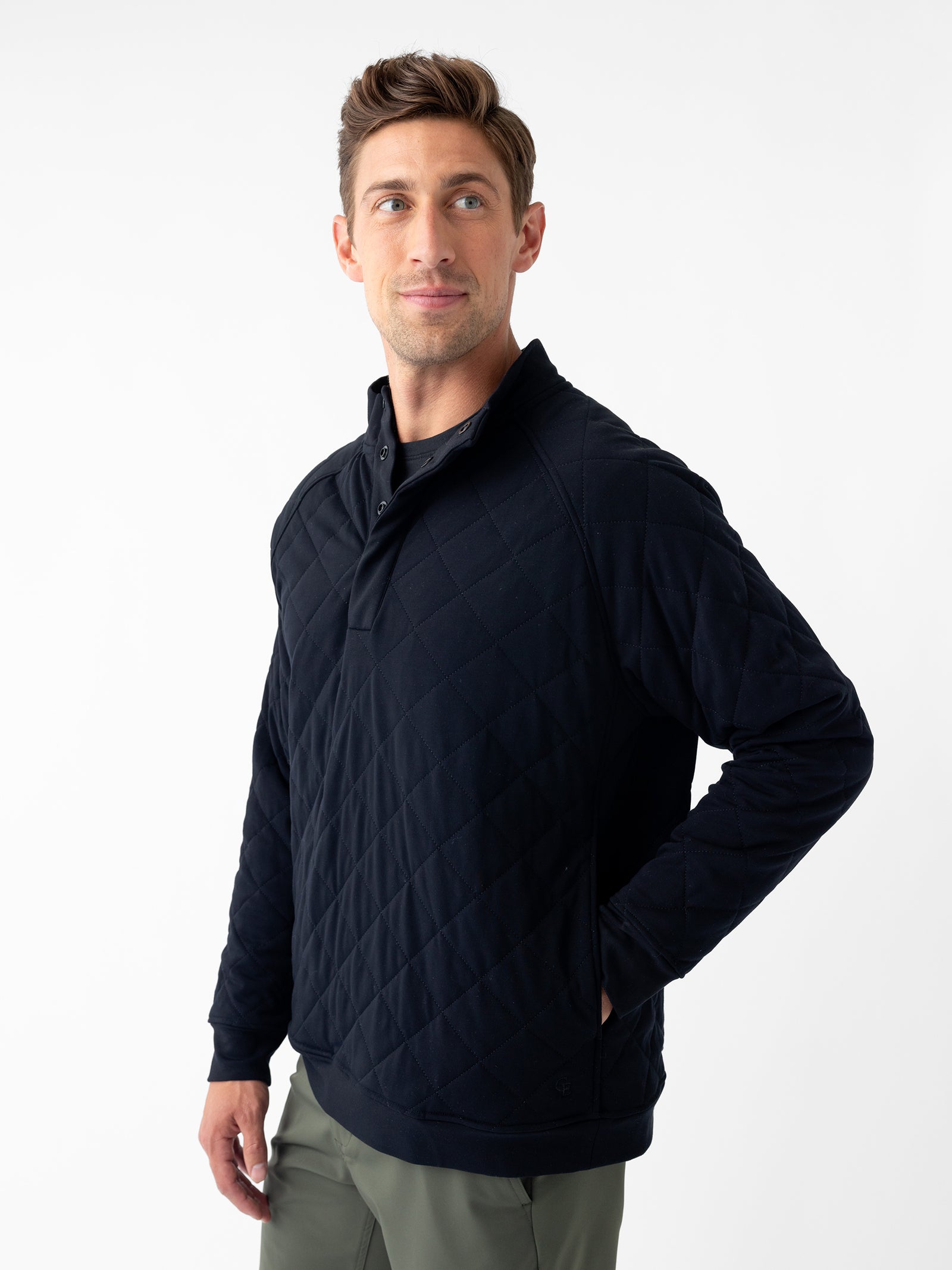 A person wearing a Cozy Earth Men's Ultra-Soft Bamboo Quilted Snap Pullover stands against a white background. The individual has short brown hair and a focused expression, with their right hand resting on their hip and looking slightly to the side.