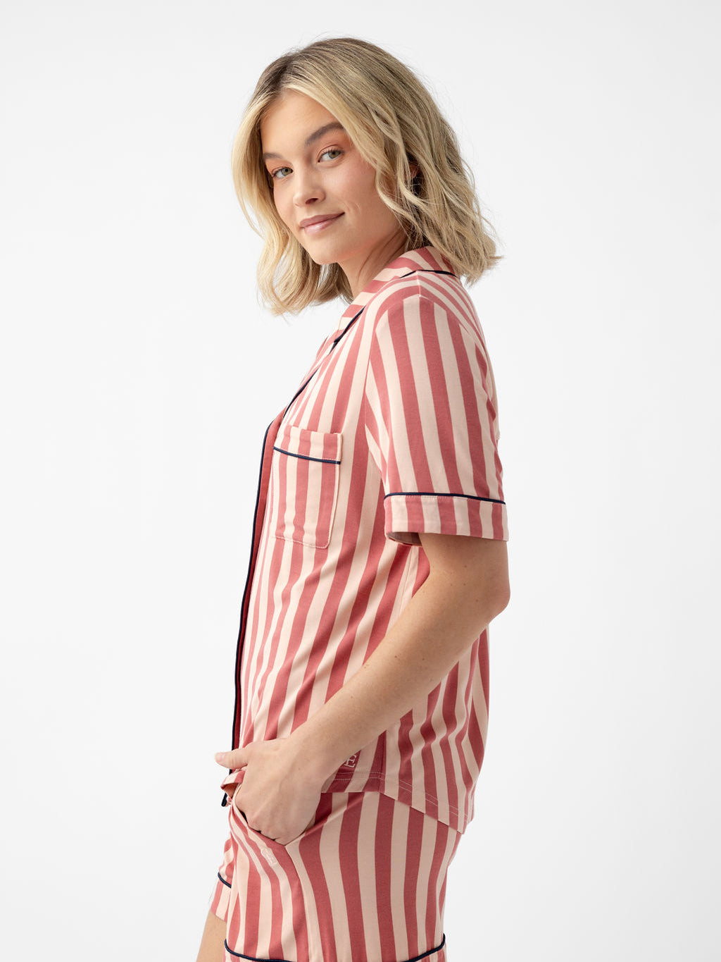 Woman wearing blush stripe short sleeve pajama top with white background